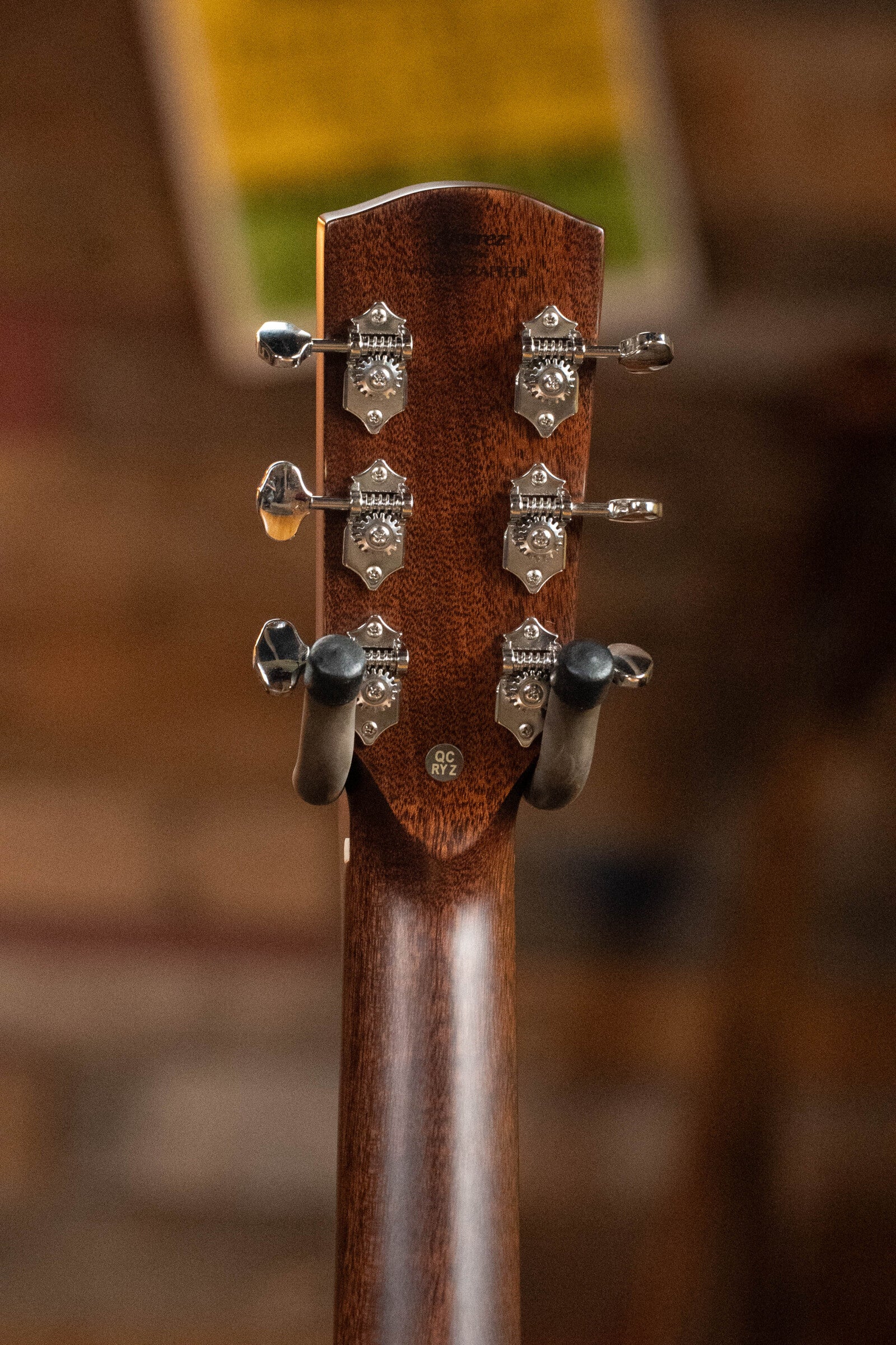Close-up of the Alvarez Laureate Series LD70e Herringbone Sunset Sitka/Rosewood Dreadnought Guitar headstock, showing six tuning pegs and part of the wooden neck, with a blurred background.