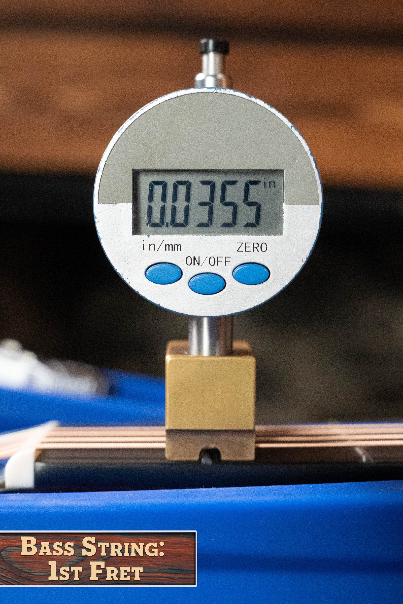A digital gauge shows a 0.0355-inch height above the first fret of a bass string, labeled "Bass String: 1st Fret," on a blue Alvarez Laureate Series LD70e Herringbone Sunset Sitka/Rosewood Dreadnought Guitar w/LR Baggs Hifi Pickup.