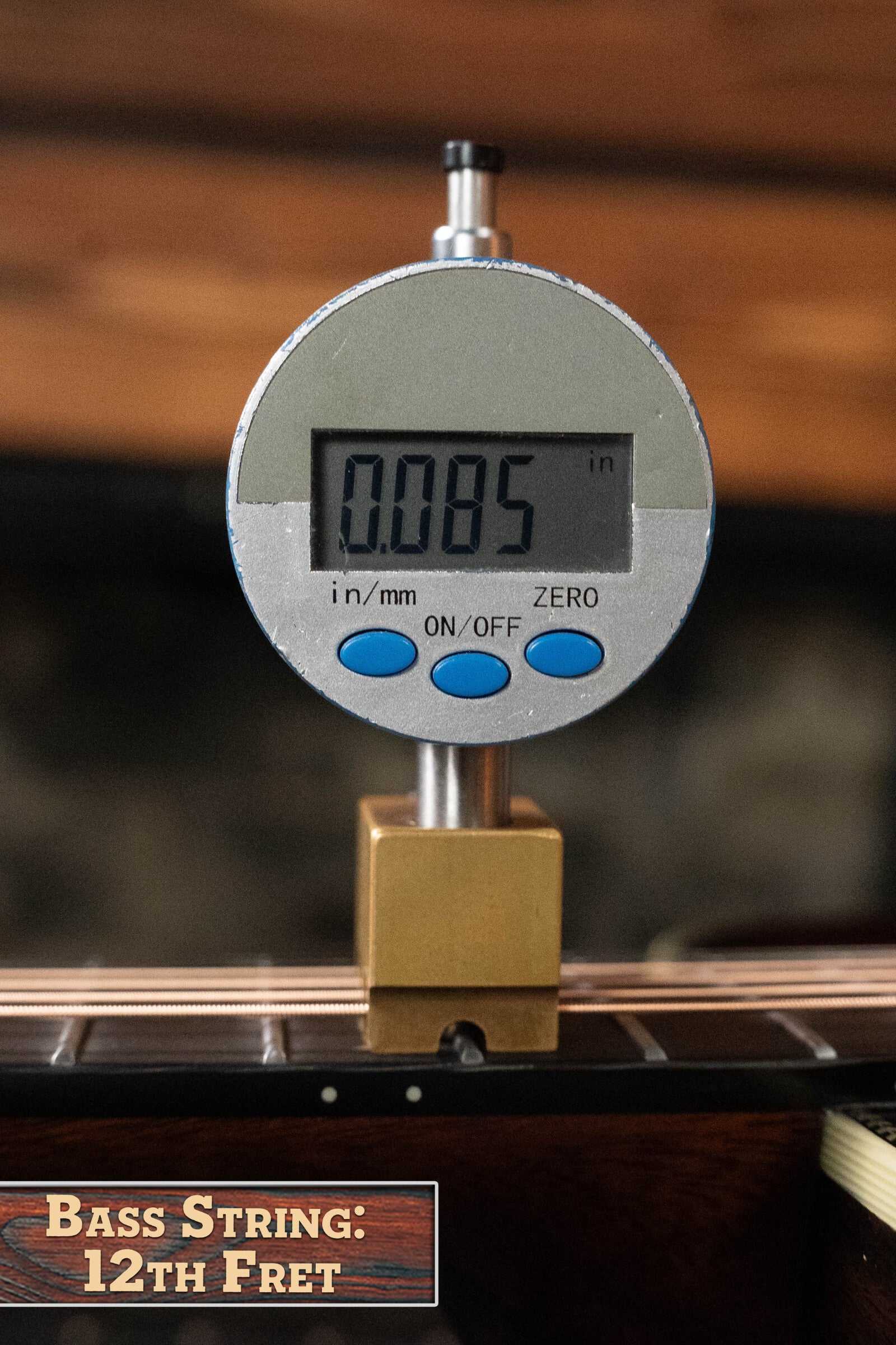 A digital gauge reads 0.085 inches while measuring the bass string height at the 12th fret, labeled “Bass String: 12th Fret,” similar to the Alvarez Laureate Series LD70e Herringbone Sunset Dreadnought Guitar w/LR Baggs.