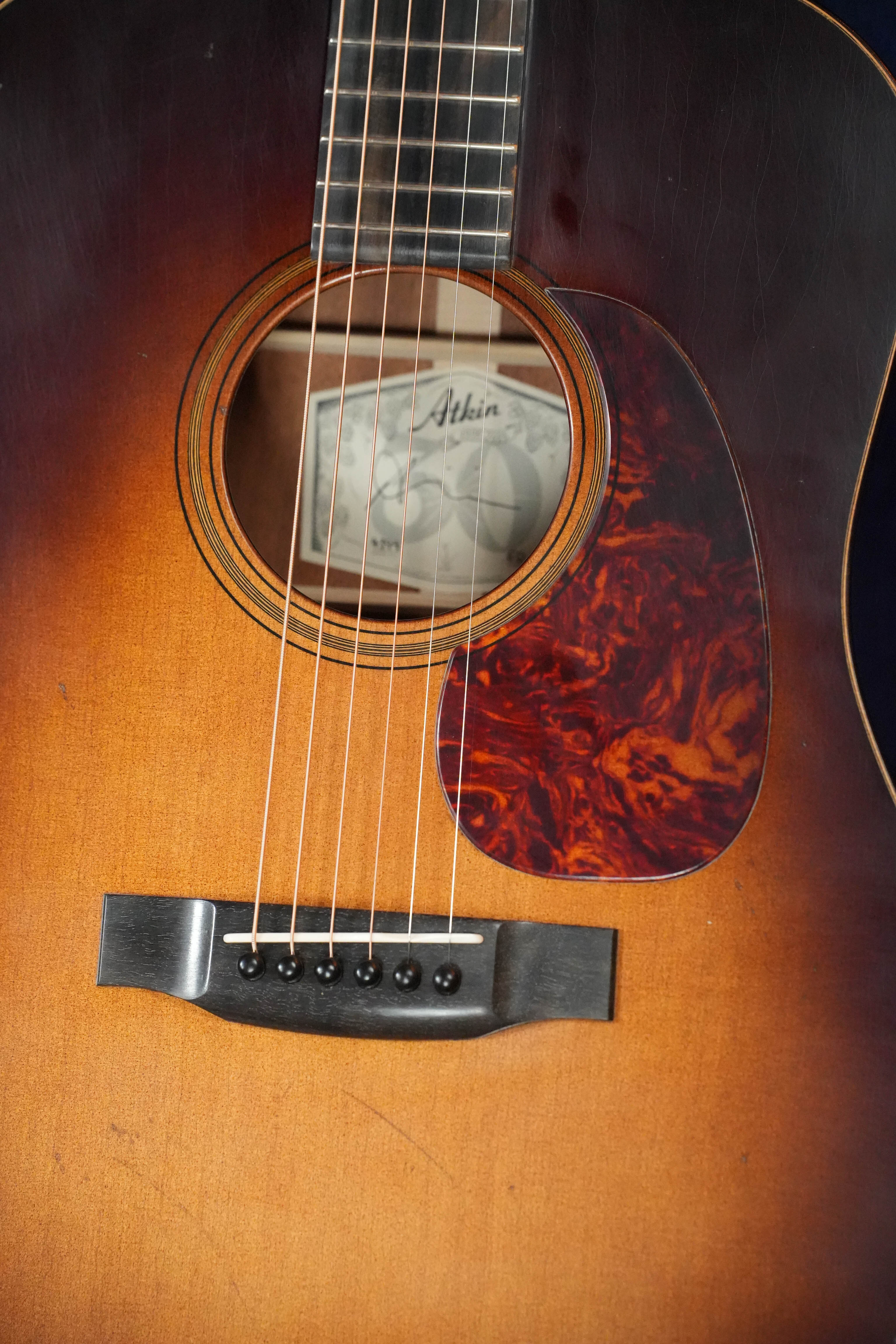 Close-up of the Atkin Guitars Essential D 45MM Sitka/Mahogany Dreadnought Acoustic Guitar #4399, featuring strings, bridge, tortoiseshell pickguard, Atkin label inside the soundhole, and a warm sunburst baked Sitka spruce top.