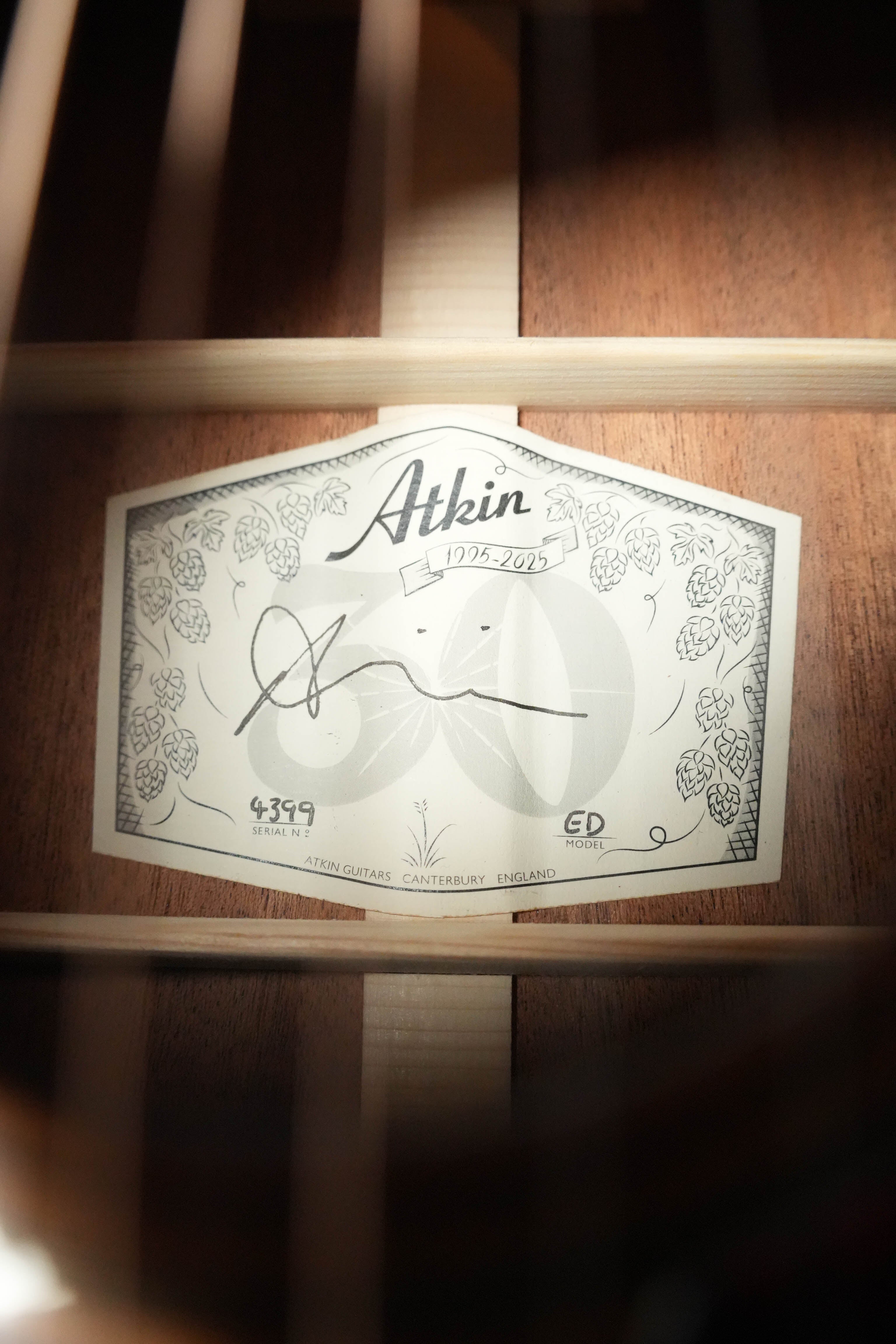 Close-up of an Atkin Guitars label inside the Essential D 45MM Sitka/Mahogany Dreadnought Acoustic Guitar #4399, showing the Atkin logo, decorative design, signatures, and “Atkin Guitars, Canterbury, England” text.