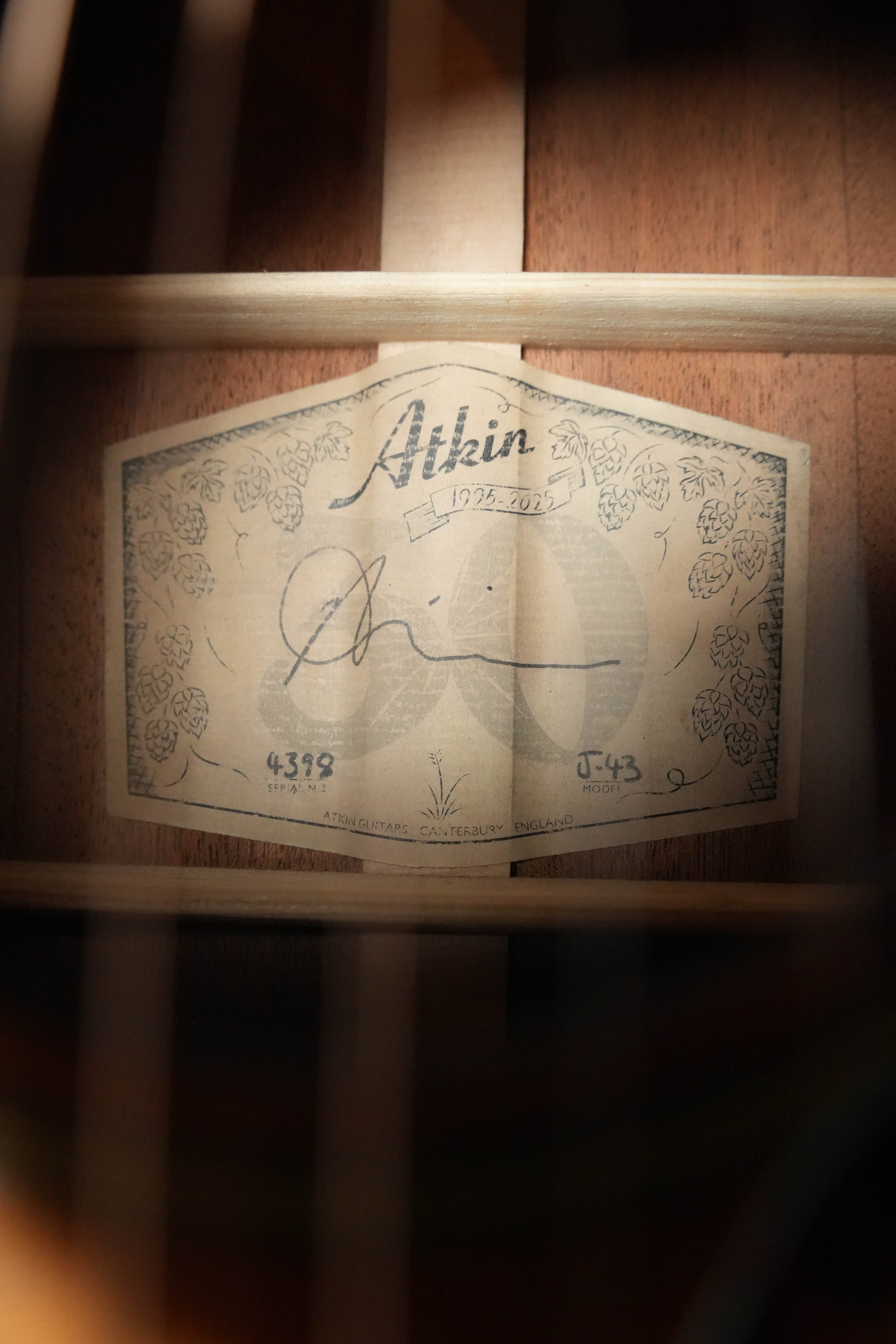 A close-up of the Atkin Guitars J43 45MM Baked Sitka/Mahogany Heavy Aged Slope Shoulder Dreadnought Acoustic Guitar #4398 interior label, featuring the brand, floral designs, signature, serial number, and wooden brace-framed detailing.