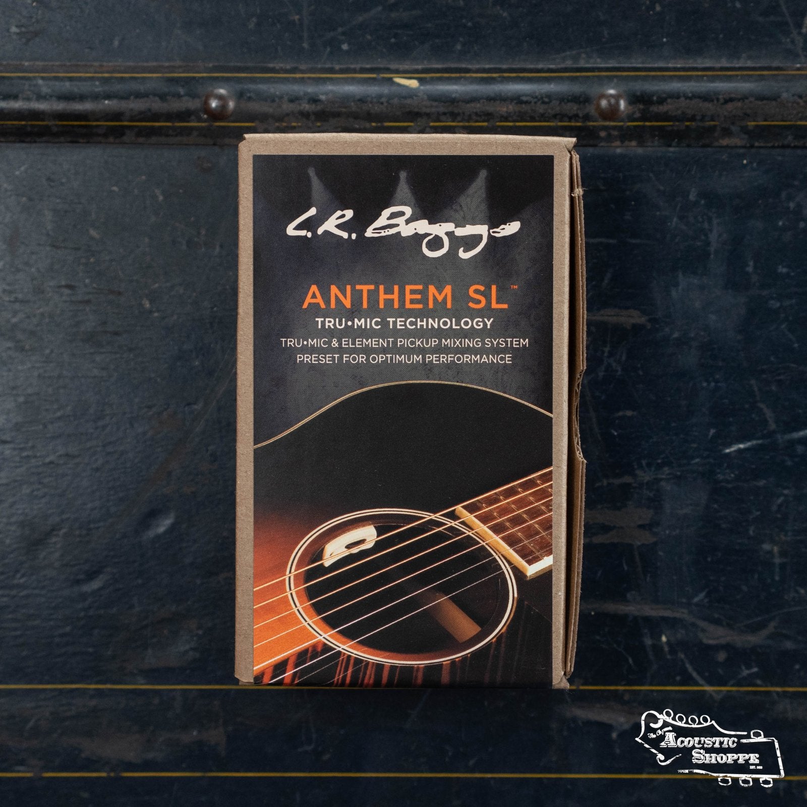 A box of the L.R. Baggs Anthem SL, showing an acoustic guitar soundhole with TRU•MIC and Element Pickup details and L.R. Baggs branding, rests on a dark textured surface with the Acoustic Shoppe logo in the corner.
