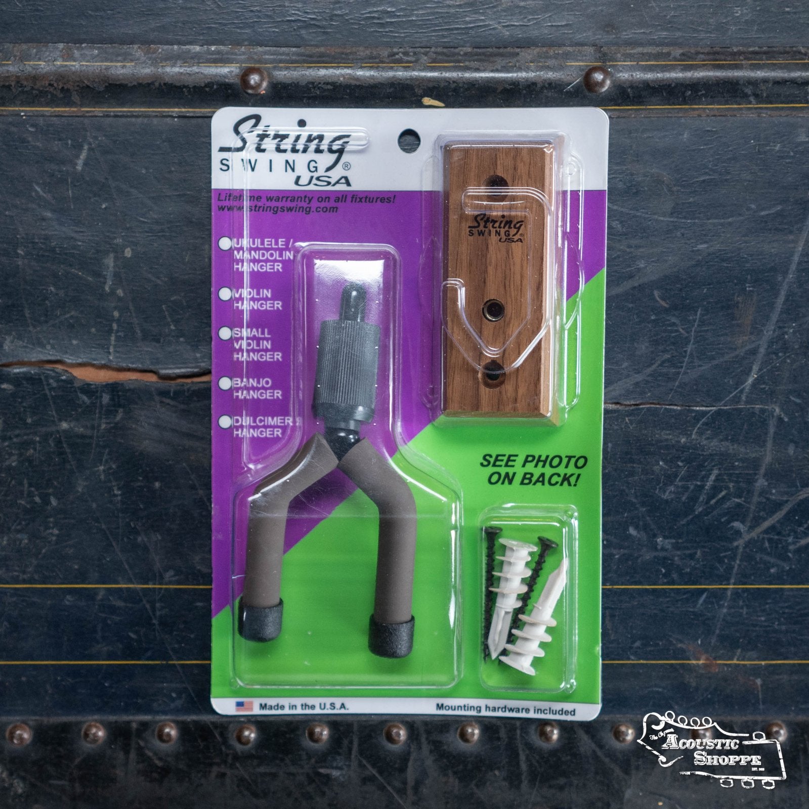 The String Swing Home & Studio Banjo/Mandolin Hanger in Black Walnut by String Swing includes a padded metal hanger, wooden mounting block, screws, and wall anchors—perfect for wall-mounting your banjo and shown on a dark, textured surface from the Acoustic Shoppe.