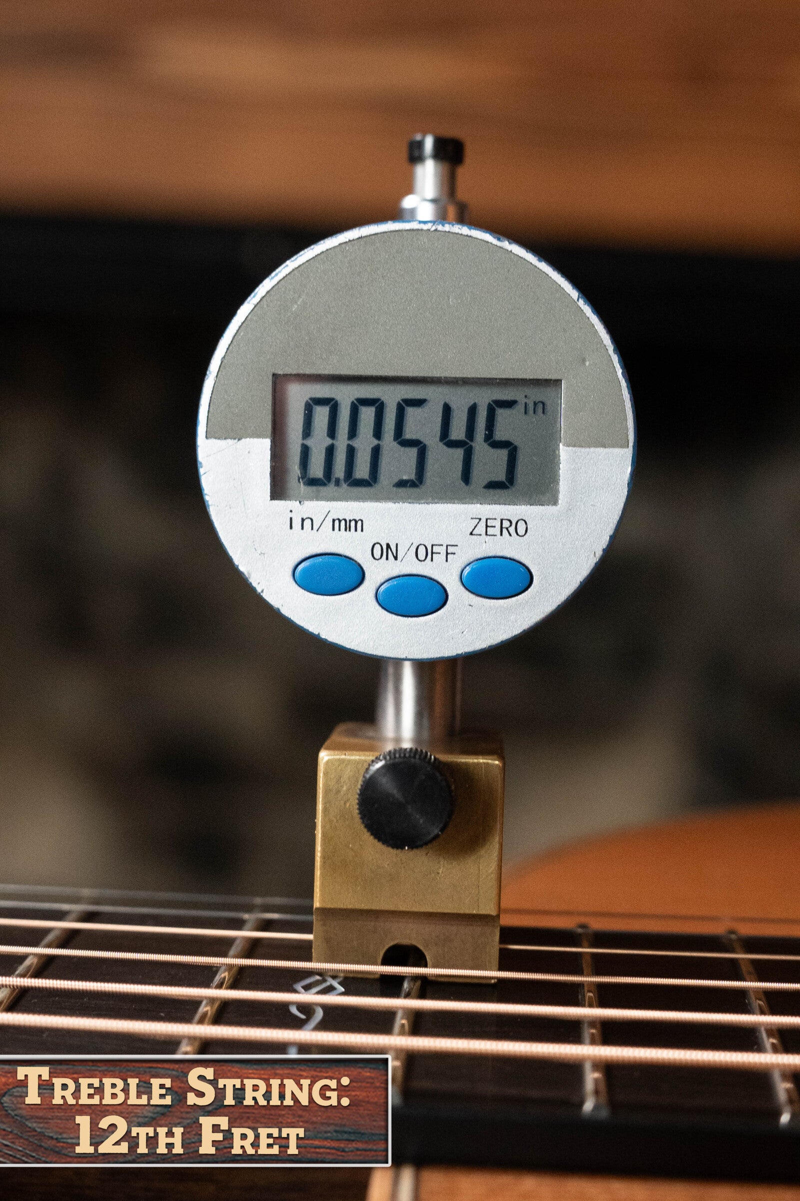 A digital caliper shows 0.0545 inches at the 12th fret treble string of a Bedell Angelica Bellissima Red Cedar/Rosewood Parlor Guitar w/K&K Pure Mini Pickup #5002. A label below reads, “Treble String: 12th Fret.”.