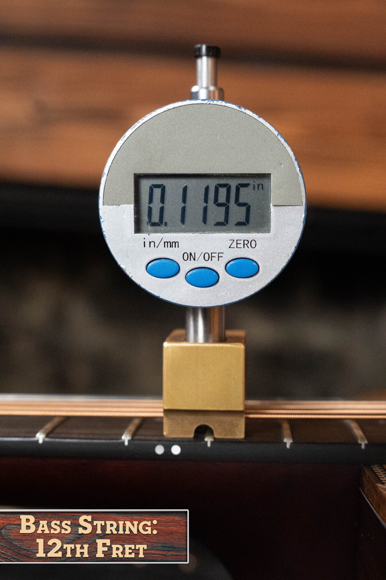 A digital gauge shows 0.1195 inches above the 12th fret of a Boucher BG-52-GM Bluegrass Goose Series Dreadnought by Boucher Guitars, with a label reading Bass String: 12th Fret.