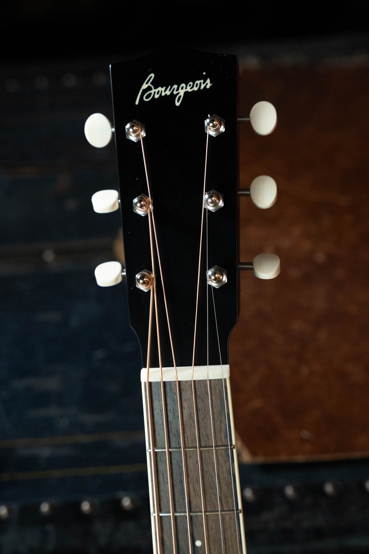 Close-up of the headstock of the Bourgeois Blues PSBB-LDBO-S Satin Professional Series All Mahogany OO Acoustic Guitar #1197, showing six tuning pegs, strings, and the Bourgeois logo on a dark background.