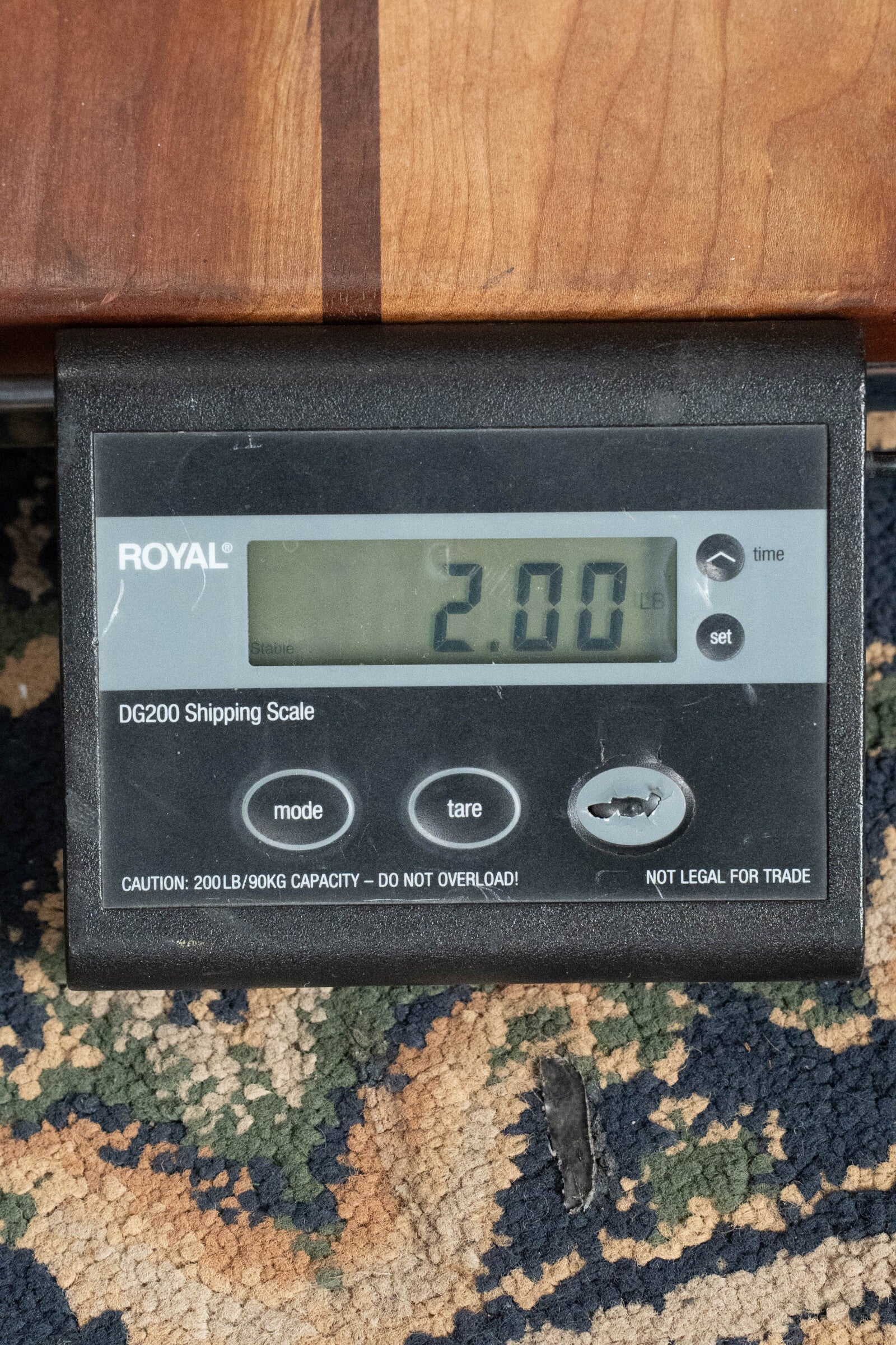 A Bourgeois M5-A-BT Aged-Tone Black Top A-Style Mandolin #2020 sits on a patterned carpet beside a ROYAL DG200 digital shipping scale displaying 2.00 pounds.