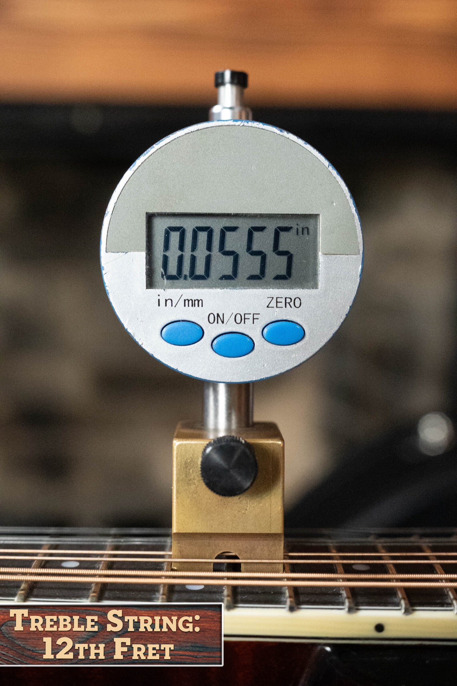 A digital gauge reads 0.0555 inches on a Bourgeois M5-A-BT Aged-Tone Black Top A-Style Mandolin #2020’s treble string at the 12th fret—ideal for precise setup checks on this Bourgeois instrument.