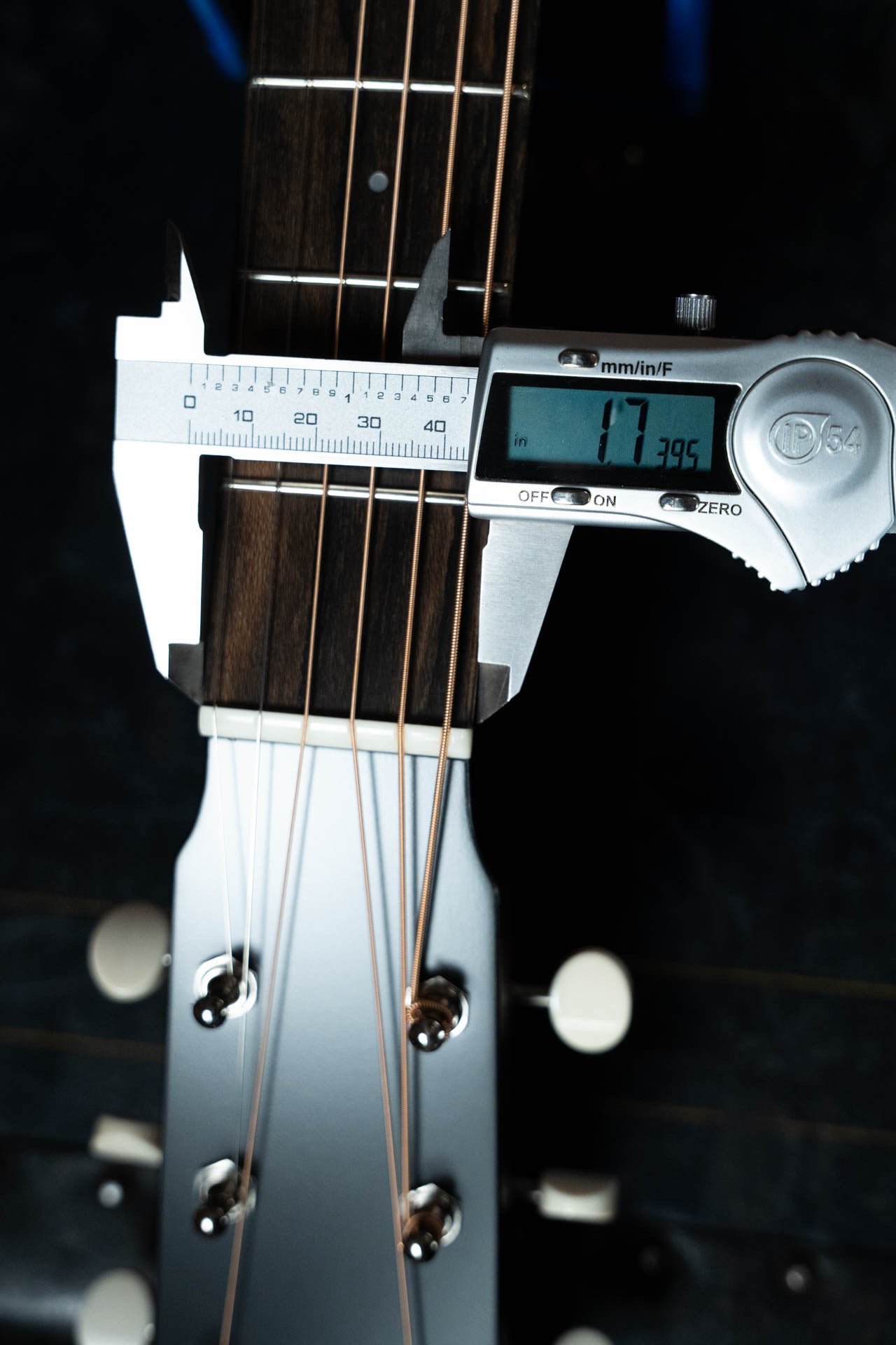 A digital caliper shows 47.39 mm measuring the neck width of the Boucher Guitars Bourgeois PSN-SD-S Satin Professional Series Sitka/Mahogany Slope Shoulder Dreadnought Acoustic Guitar #1174 near the headstock, with strings and tuning pegs visible.