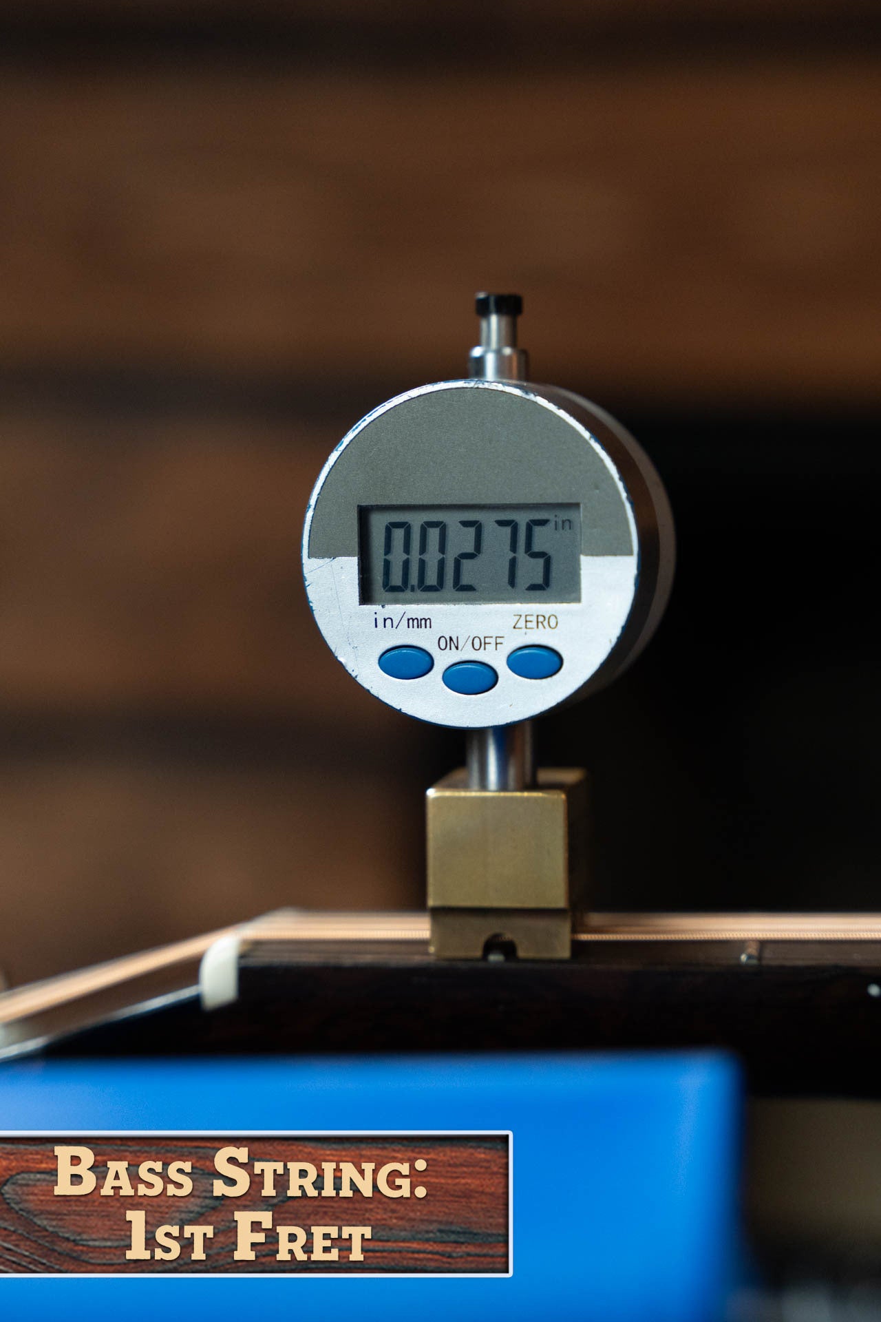 A digital gauge reads 0.0275 inches while measuring a bass guitar string at the 1st fret. A wooden sign below reads, "Bass String: 1st Fret"—evoking the precision of Boucher Guitars' Bourgeois PSN-SD-S Sitka/Mahogany Dreadnought.