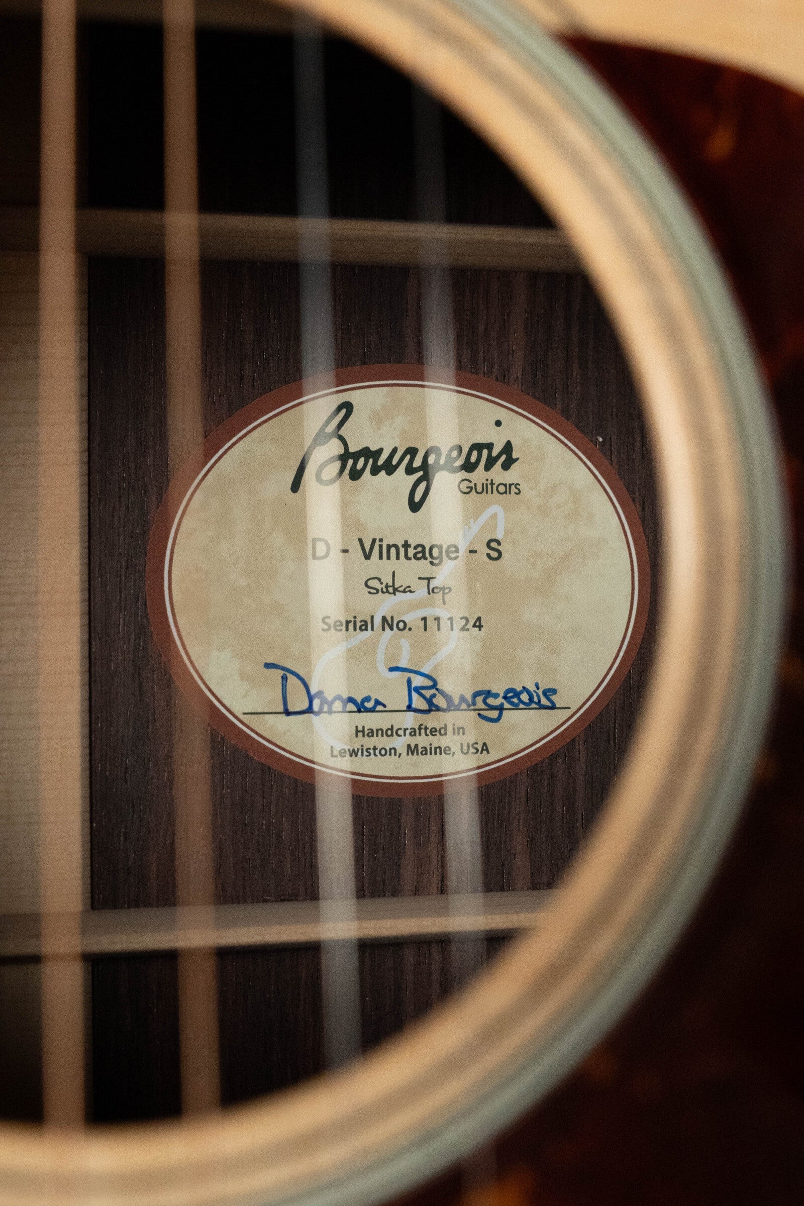 Close-up of the Bourgeois PSV-D-S Professional Series Sitka/Rosewood Vintage Satin Dreadnought Acoustic Guitar label (#1124), seen through the sound hole, featuring “Handcrafted in Lewiston, Maine, USA” with a blue signature.