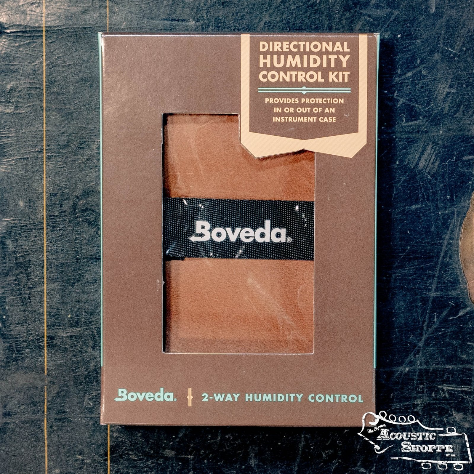 The Boveda Two-Way Humidity System Directional Humidity Control Kit by Boveda Inc. comes in a brown box with teal and gold text, plus a clear window showing the packet—ideal as a hollow body instrument humidifier.