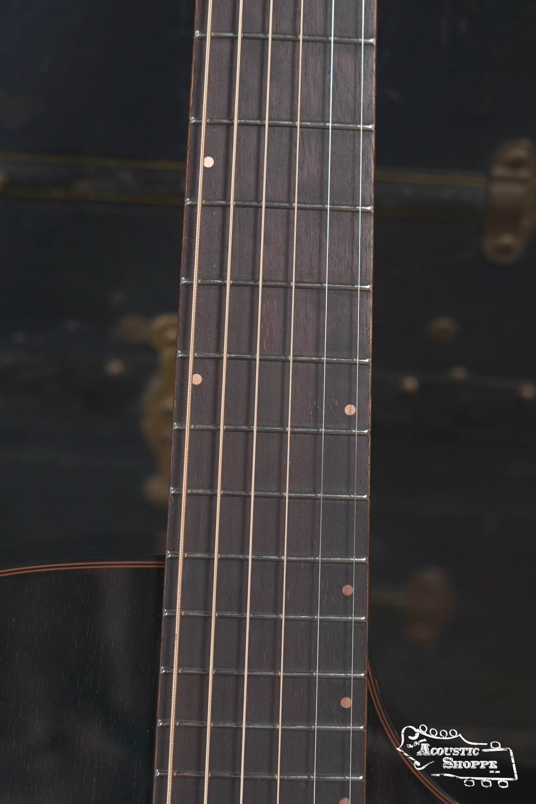 Close-up of the Breedlove Rainforest S Concert Papillon All Mahogany Cutaway’s fretboard with metal frets, dot inlays, part of the soundhole, and Acoustic Shoppe logo visible. Features EcoTonewood tech and Fishman pickup.