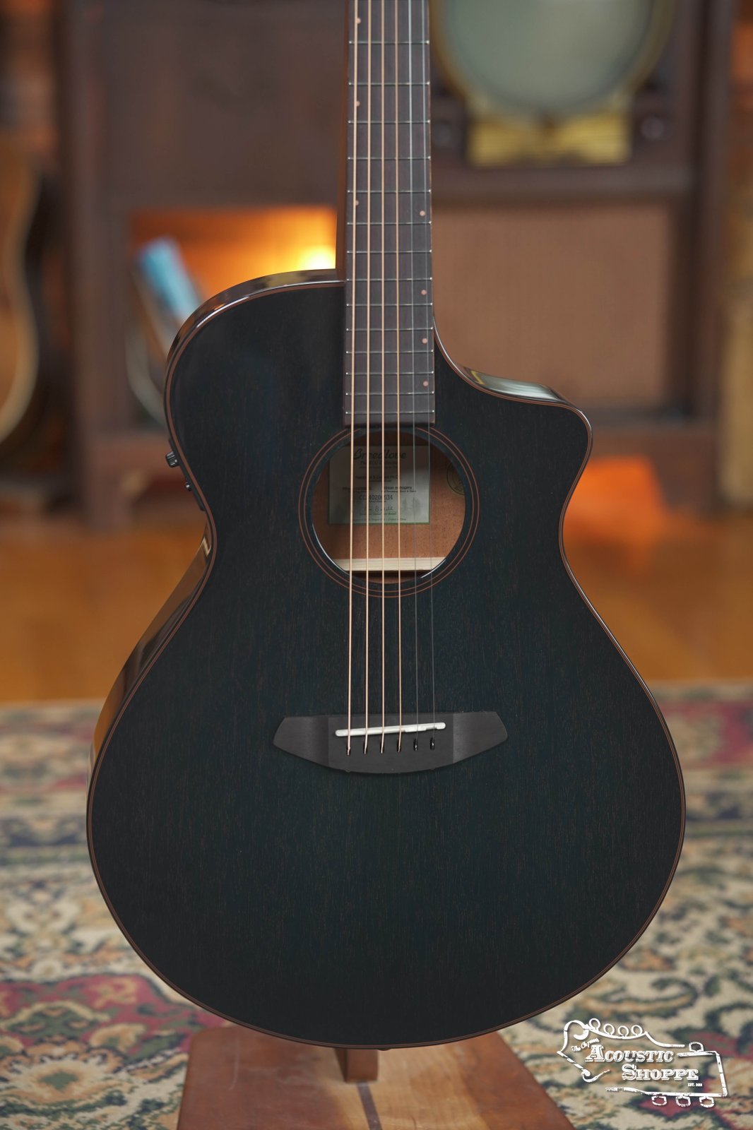 The Breedlove Rainforest S Concert Papillon All Mahogany Cutaway Acoustic Guitar w/Fishman Pickup #6534 is displayed indoors on a stand, showcasing EcoTonewood tech and a modern bridge, with vintage gear and a patterned rug in the background.