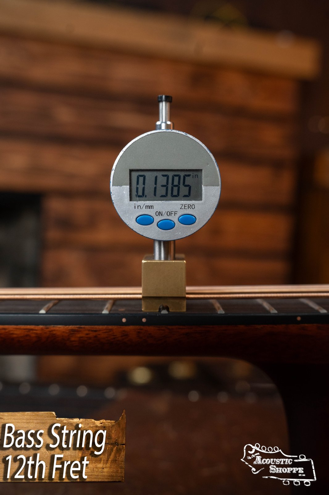 A digital caliper shows the bass string height at the 12th fret as 0.1385" on a Breedlove Organic Solo Pro Concerto Red Cedar/African Mahogany Acoustic Bass, with “Bass String 12th Fret” text and the Acoustic Shoppe logo in the corner.
