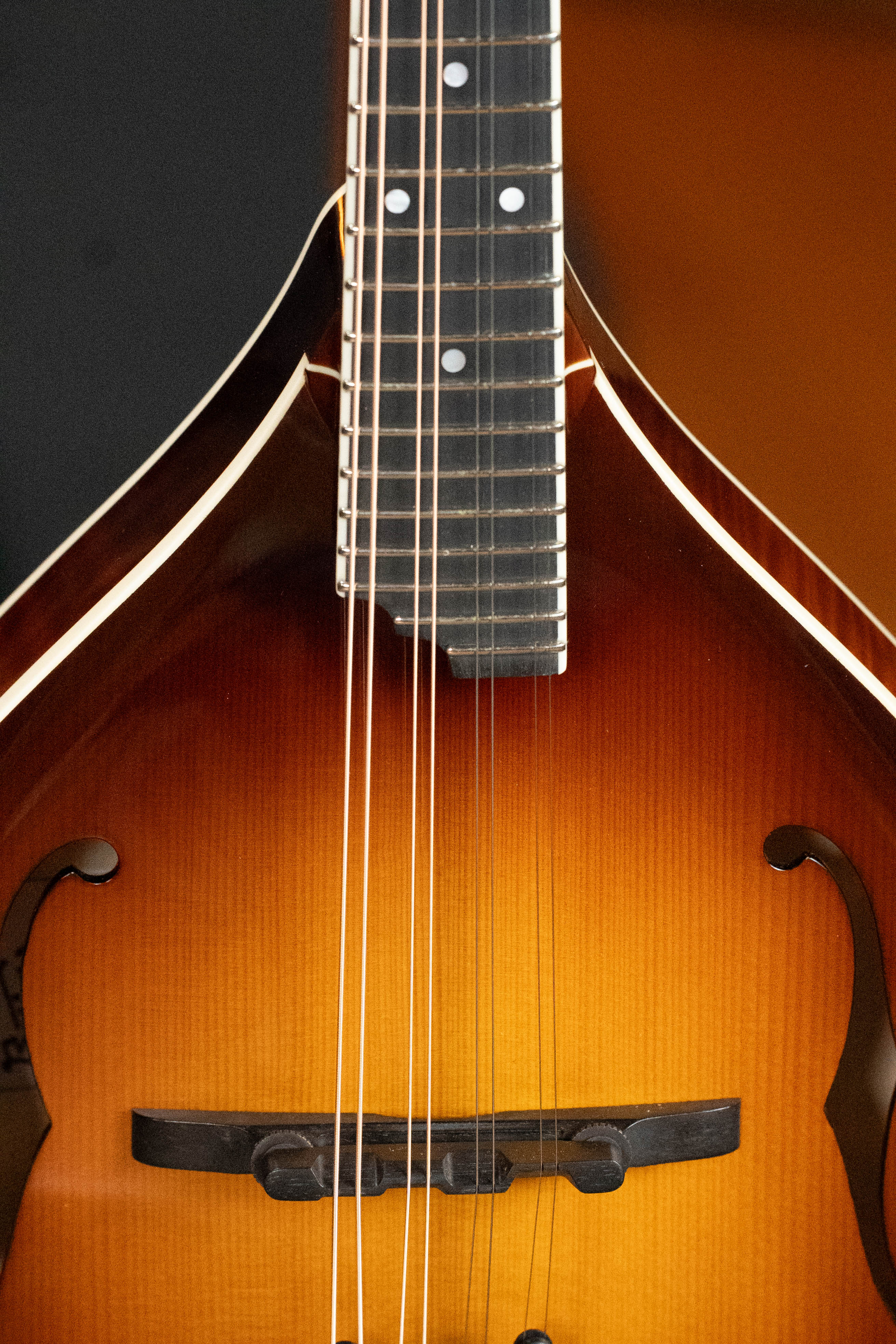 Close-up of the Bulas Carpathian Spruce/Curly Maple Cremona Sunburst A-Style Mandolin #8129, highlighting its strings, f-holes, and wood grain on the body and neck.