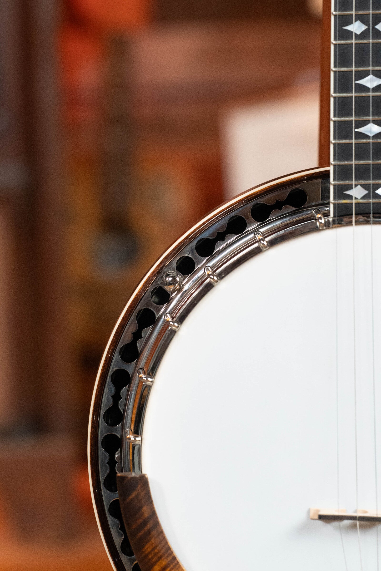 Close-up of the Bulas Standard 5-String Tobacco Sunburst Resonator Banjo #0676, showing its circular white drumhead, metal rim, and neck with pearl inlays. Brand: Bulas. Background is softly blurred.