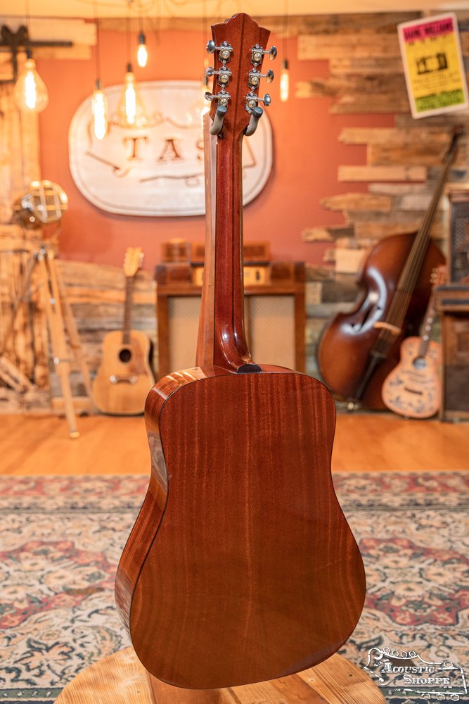 A Guild Guitars USA D-40 Traditional Sitka Spruce/African Mahogany Natural Top Dreadnought (#1106) rests on a stand in a cozy, vintage-style music room decorated with warm lighting and various instruments.