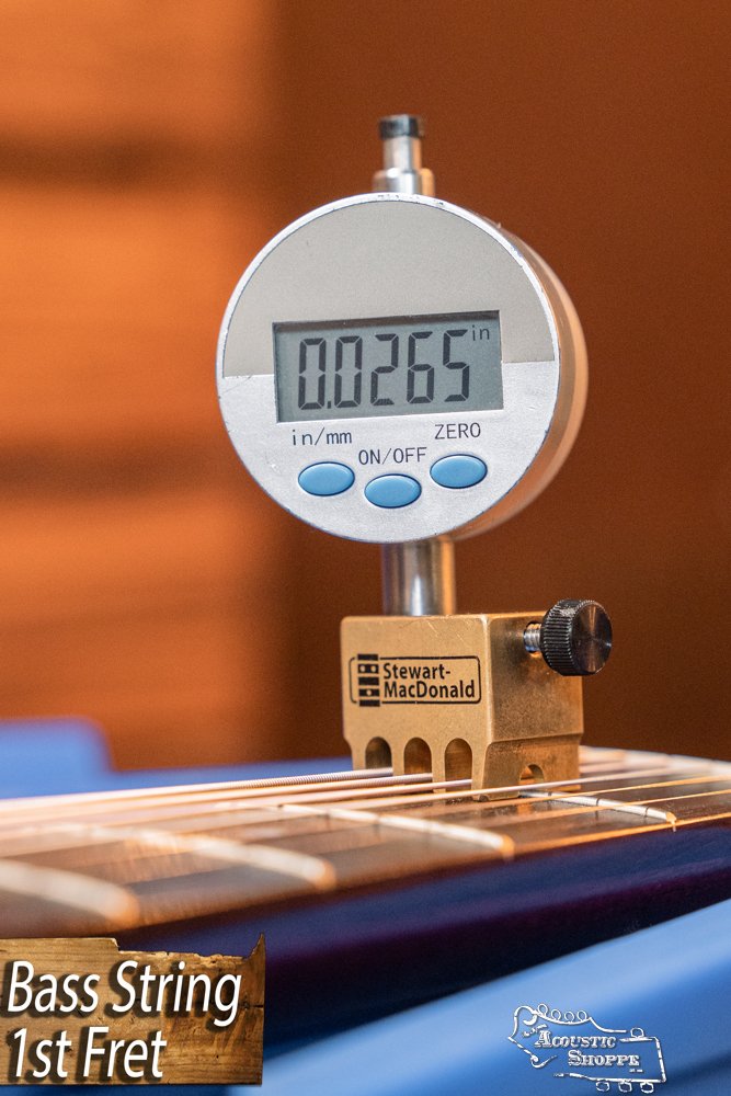A digital gauge above the string at the 1st fret of a Guild Guitars USA D-40 Traditional Dreadnought #1106 shows 0.0265 inches. The display reads "Bass String 1st Fret" with an Acoustic Shoppe logo visible.