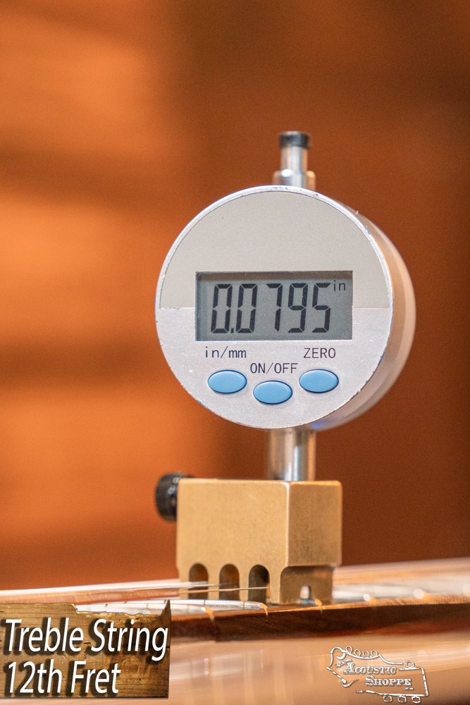 A digital gauge shows 0.0795 inches on the treble string at the 12th fret of a Guild Guitars USA D-40 Traditional Sitka Spruce/African Mahogany Natural Top Dreadnought #1106, with a blurred background and a bottom-left label visible.