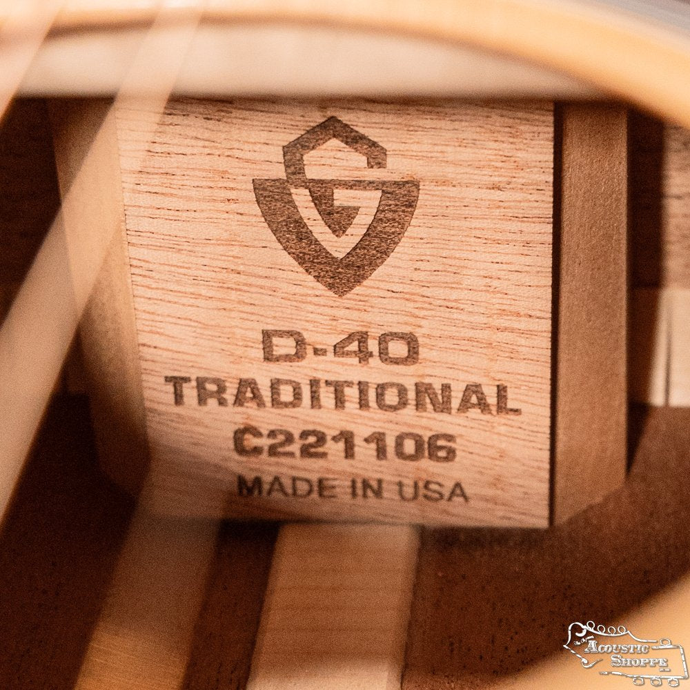 Close-up of a Guild Guitars USA D-40 Traditional Sitka Spruce/African Mahogany Natural Top Dreadnought #1106, showing its wooden label with “D-40 TRADITIONAL C221106 MADE IN USA” and a shield logo. Features a solid Sitka spruce top.