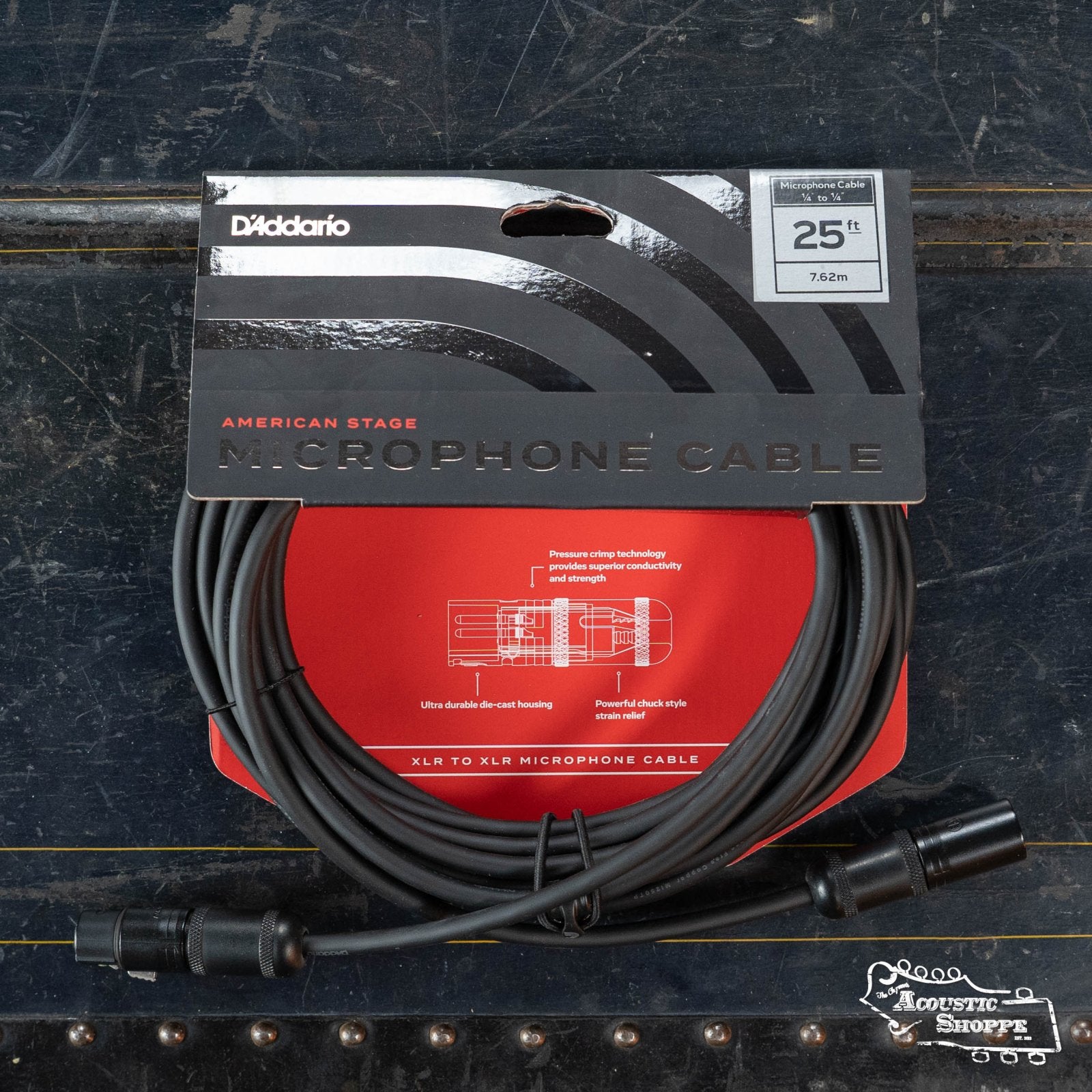 A coiled D'Addario PW-AMSM American Stage Series XLR Microphone Cable (25 ft, 7.62 m) in black packaging rests on a dark textured surface with The Acoustic Shoppe logo at bottom right, offering high-definition signal clarity.