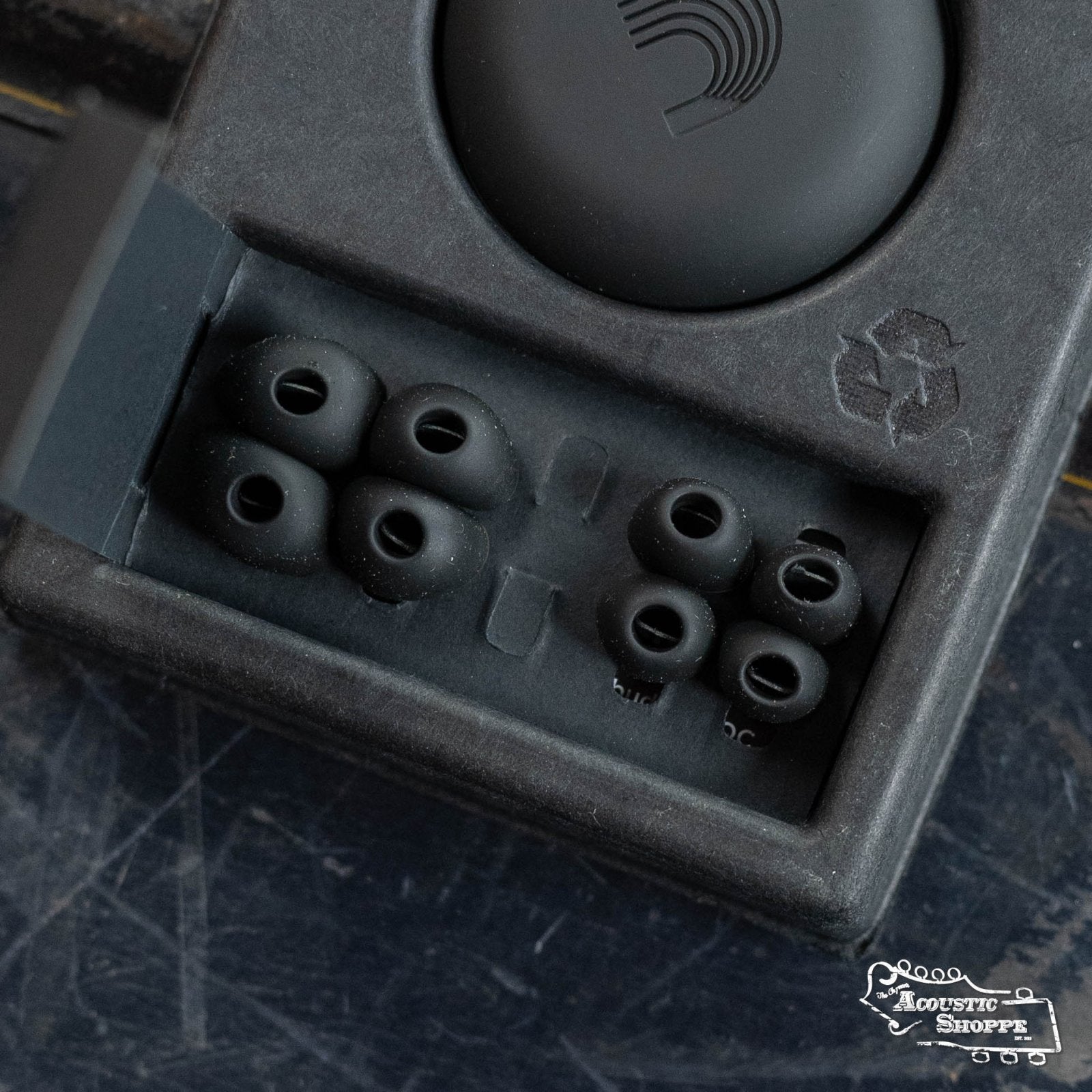 The DAddario PW-DBUDHP-01 Bud Premium Hearing Protection includes a black tray with three pairs of black earbud tips in different sizes and a round case, all in recyclable cardboard packaging.