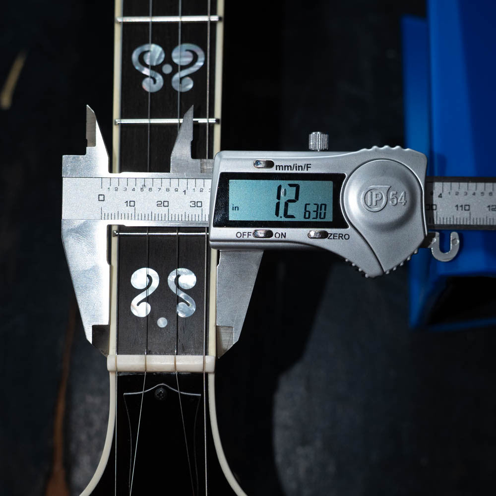 A digital caliper shows a 42.63 mm neck width at the nut on the Deering Banjos Calico 5 String Curly Maple Resonator Banjo w/Spikes Installed #AX45, which features decorative fretboard inlays near the nut.