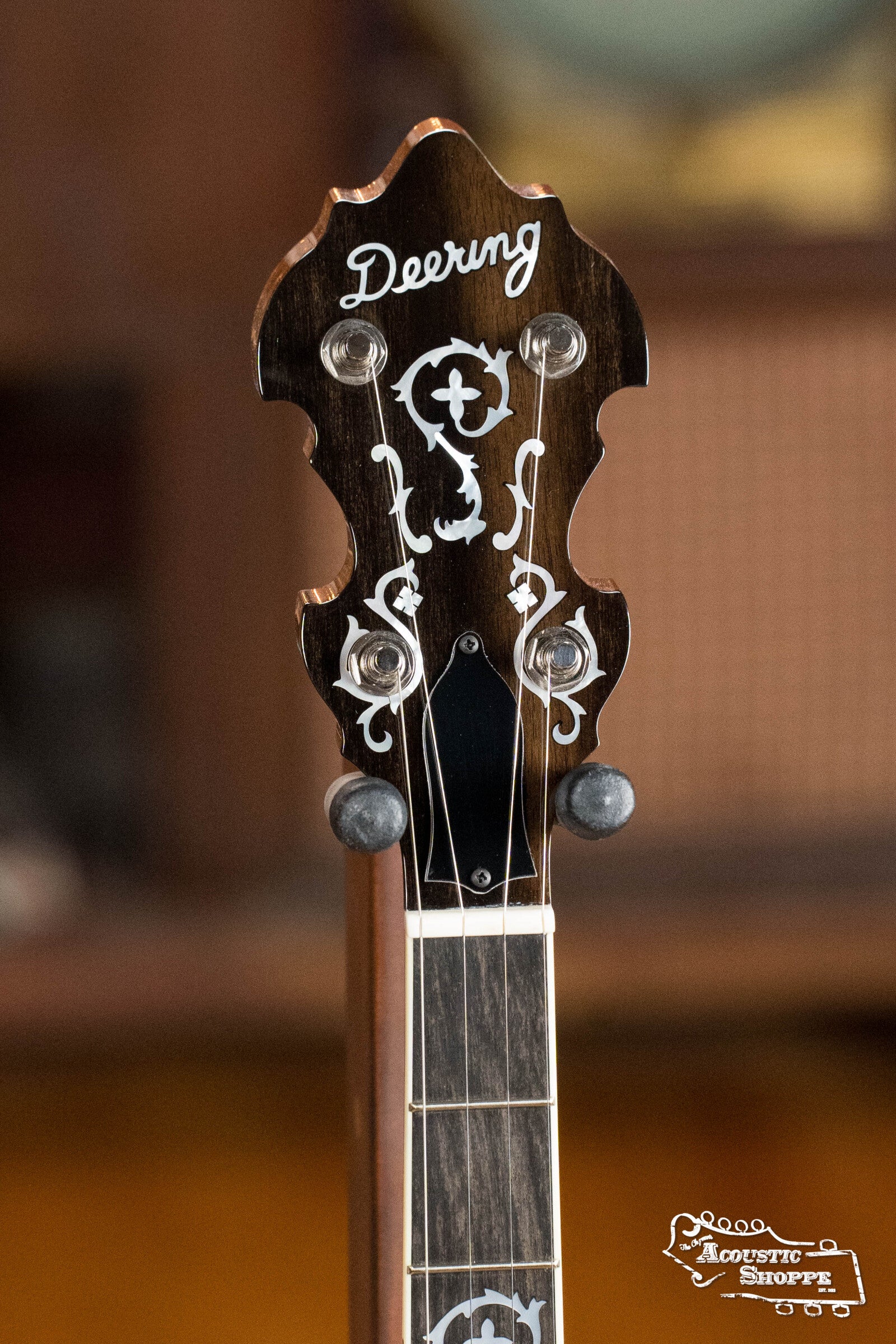 Close-up of the Deering Golden Wreath 5 String Resonator Banjo #AU47 by Deering Banjos, featuring ornate white inlays, tuning pegs, and the Deering logo on a dark wood headstock—perfect for bluegrass.