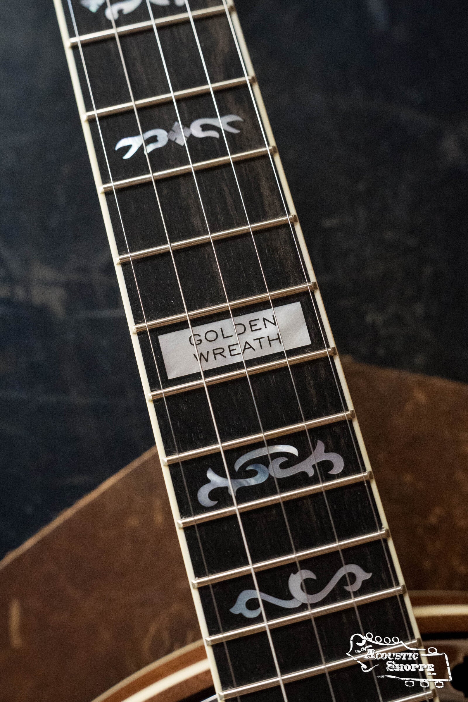 Close-up of a banjo fretboard with intricate inlays, including a rectangular one reading GOLDEN WREATH. The style matches the Deering Golden Wreath 5 String Resonator Banjo #AU47 by Deering Banjos; the banjo body is partially visible in the background.