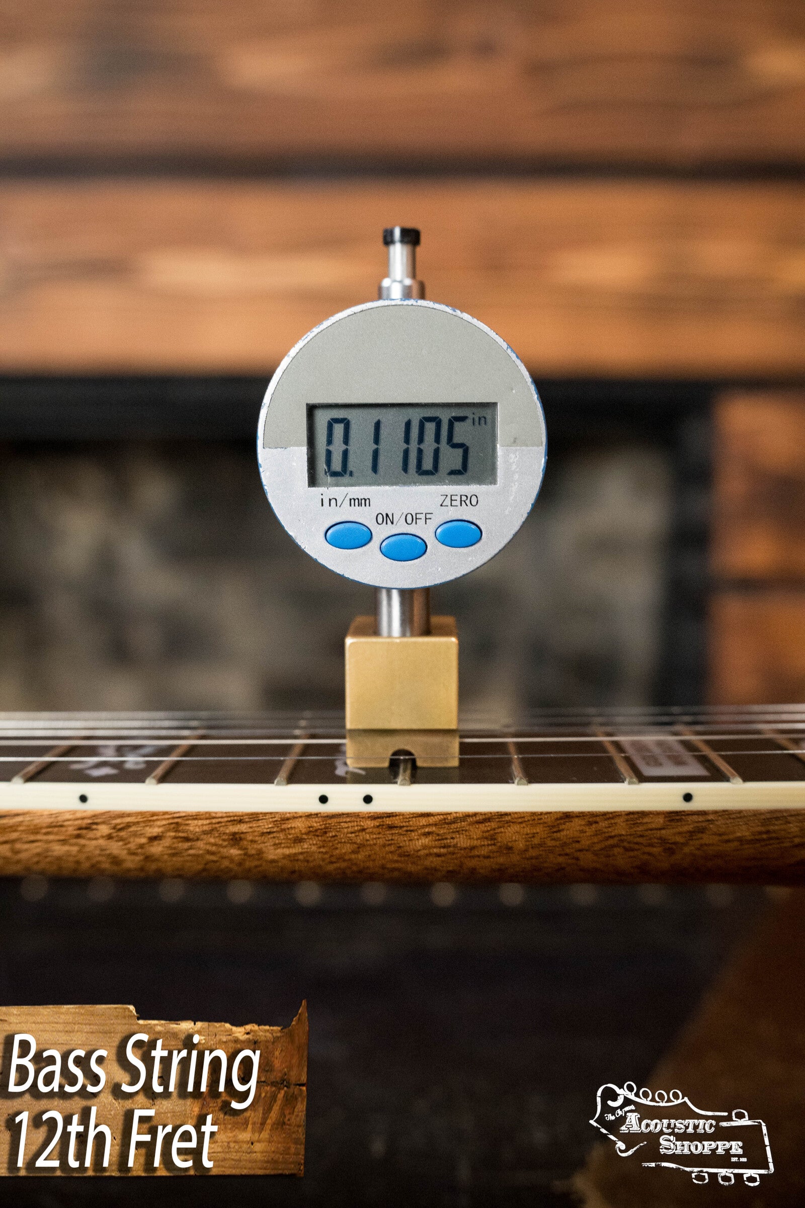 A digital gauge shows the bass string height at the 12th fret of a Deering Golden Wreath 5 String Resonator Banjo (#AU47) from Deering Banjos as 0.1105 inches. Bass String 12th Fret and The Acoustic Shoppe logo are in the corners.