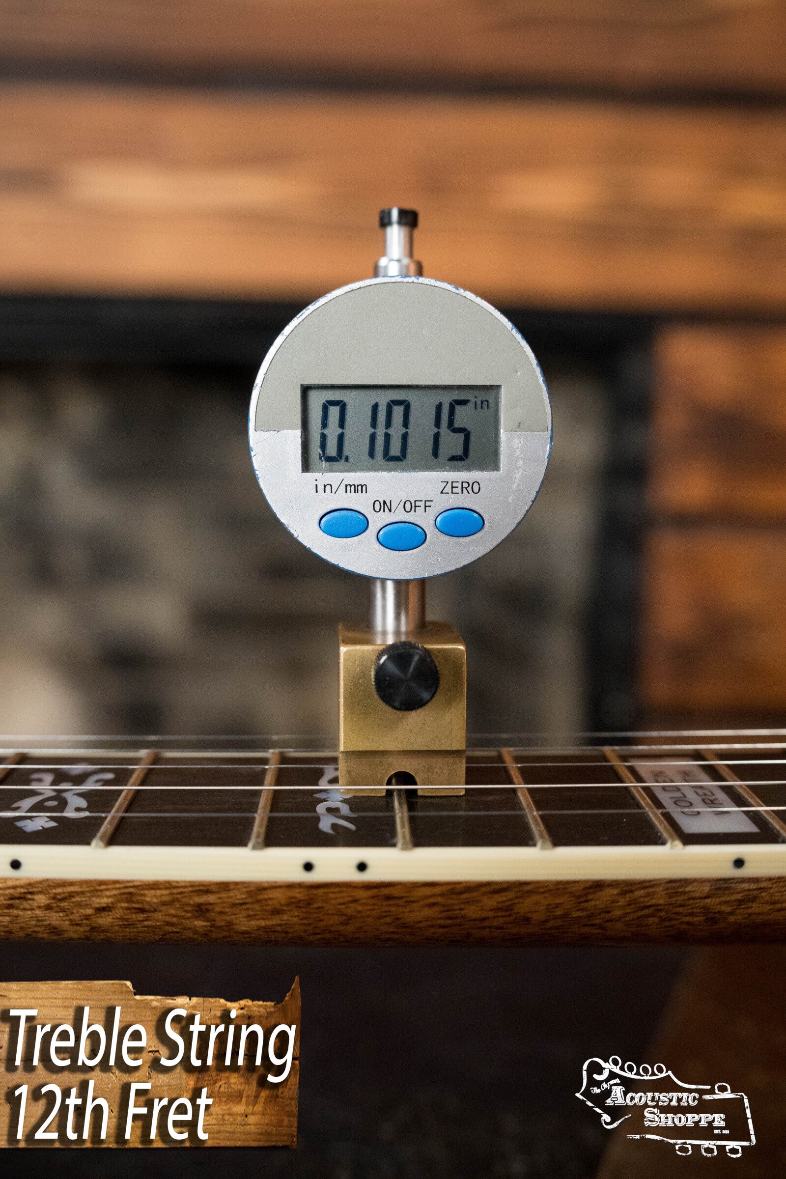 A digital caliper shows 0.1015 string height at the 12th fret of a Deering Golden Wreath 5 String Resonator Banjo #AU47 by Deering Banjos. Treble String 12th Fret and the Acoustic Shoppe logo are visible in the image.