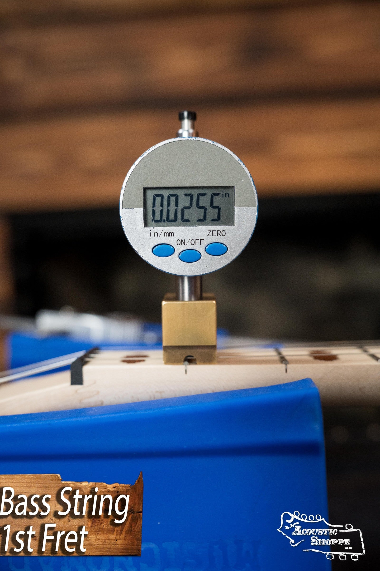 A digital caliper shows a bass string height of 0.0255 at the 1st fret, with a “Bass String 1st Fret” label, The Acoustic Shoppe logo, and a Deering Goodtime Deco 5-String Banjo #52407 by Deering Banjos in the background.
