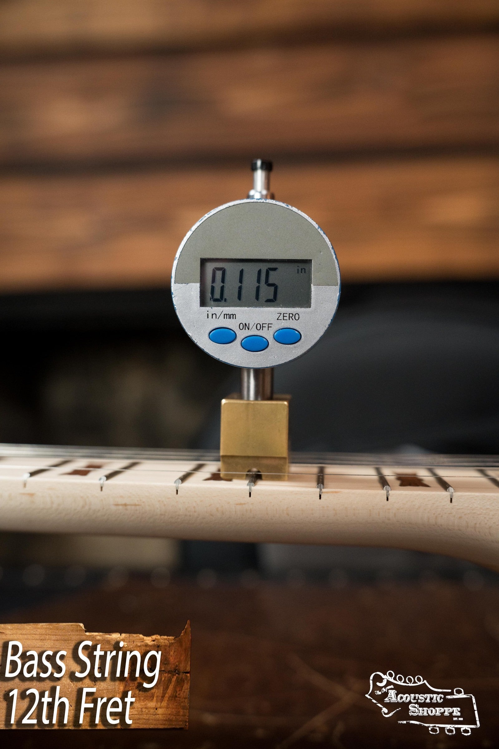 A digital caliper shows a 0.115-inch string height above the 12th fret on a Deering Goodtime Deco 5-String Banjo (#52407) by Deering Banjos. Text reads Banjo String 12th Fret and the Acoustic Shoppe logo is displayed.