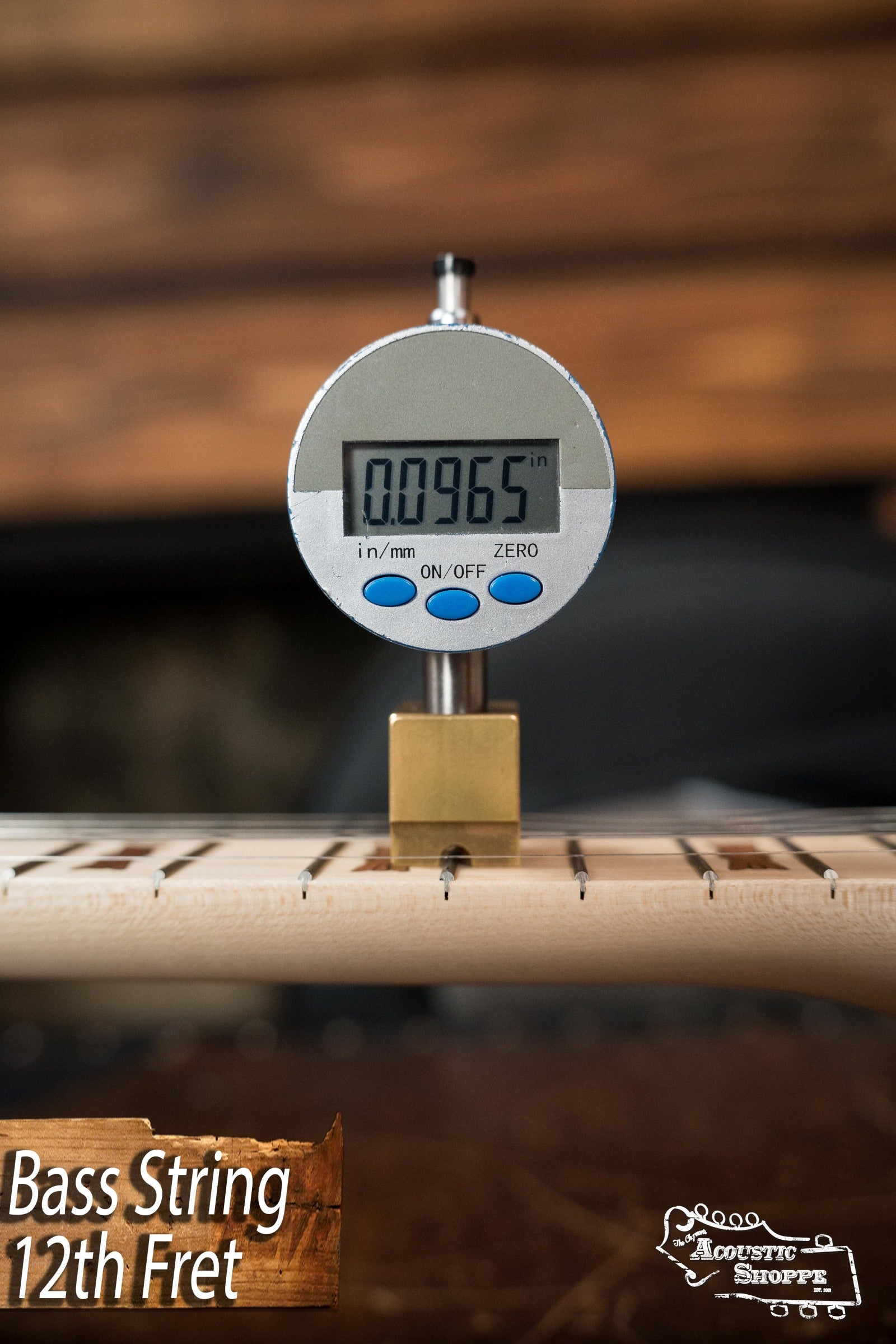A digital gauge shows the Deering Goodtime Deco 5-String Banjo #62407’s bass string height at the 12th fret as 0.0965 inches. “Bass String 12th Fret” and “Acoustic Shoppe” appear in the corners. Brand: Deering Banjos.