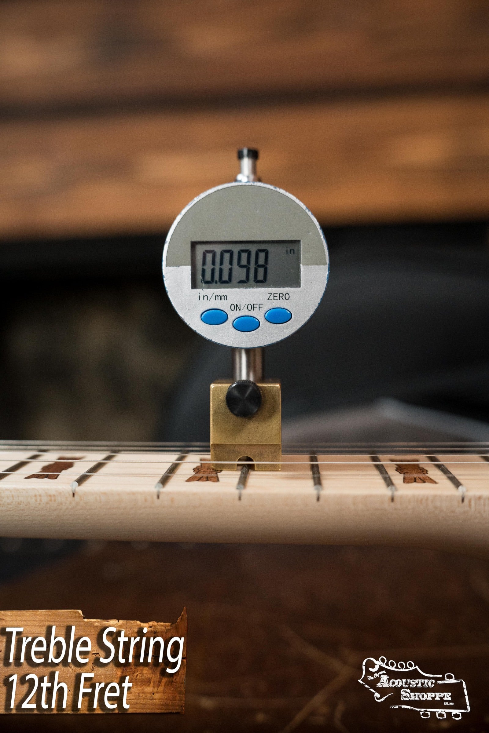 A digital gauge reading 0.098 inches is positioned above the 12th fret treble string on a Deering Goodtime Deco 5-String Banjo #62407 by Deering Banjos. Treble String 12th Fret and Acoustic Shoppe appear in the lower corners.