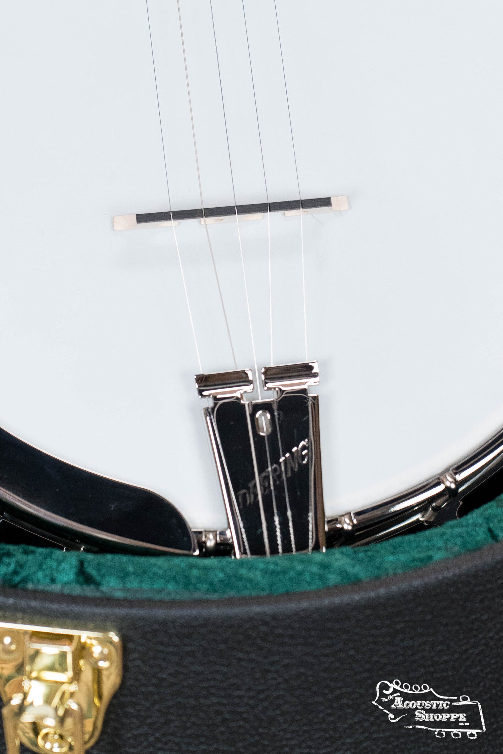 Close-up of a Deering Banjos Rustic Wreath 5-String Resonator Banjo #AU45 body, showing the bridge, “DEERING” tailpiece, and green case lining. The Acoustic Shoppe logo appears in the lower right corner.
