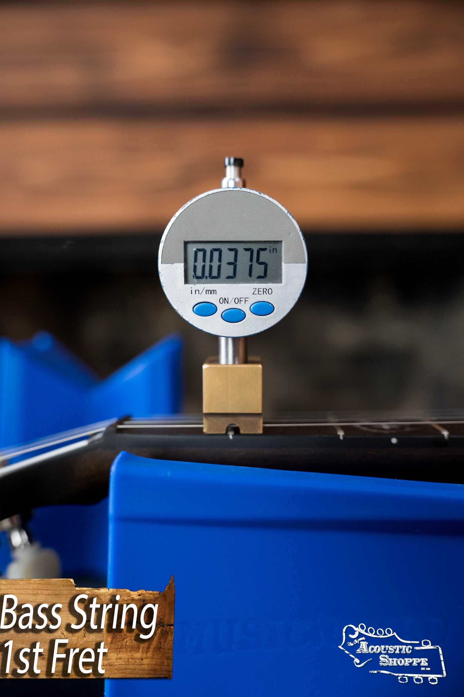 A digital gauge shows a 0.0375-inch string height at the 1st fret of the Deering Rustic Wreath 5-String Resonator Banjo #AU45 by Deering Banjos, with blue neck supports and a Bass String 1st Fret label—ideal for precise setups.