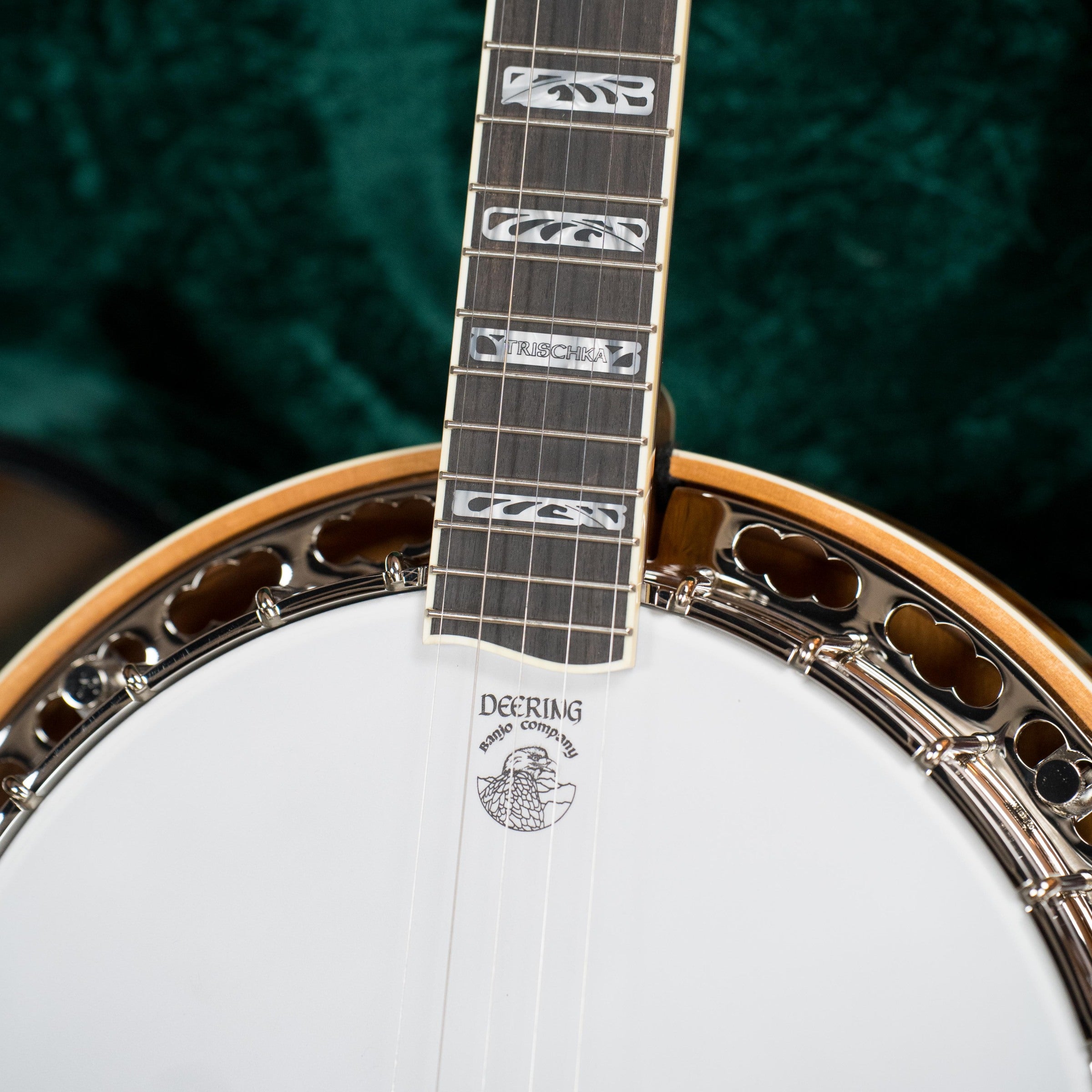 Close-up of a Deering Banjos Tony Trischka Silver Clipper Resonator Banjo w/Spikes at 7, 8, 9, and 10 (#0100), featuring ornate neck inlays, strings, and the Deering owl logo on the white drumhead—ideal for bluegrass fans.