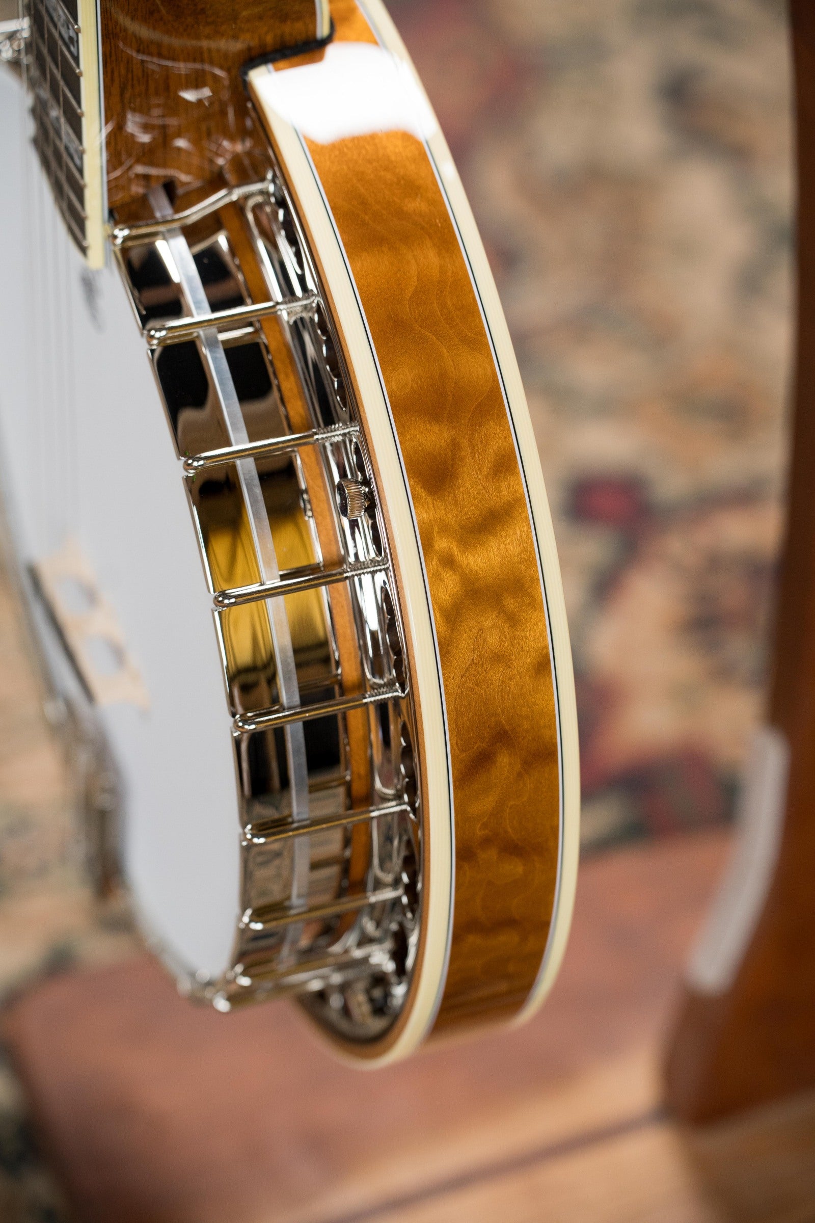 Close-up of the Deering Banjos Tony Trischka Silver Clipper Resonator Banjo w/Spikes at 7, 8, 9, and 10 (#0100), highlighting its glossy wood finish, metal hardware, and cream binding—ideal for bluegrass fans.