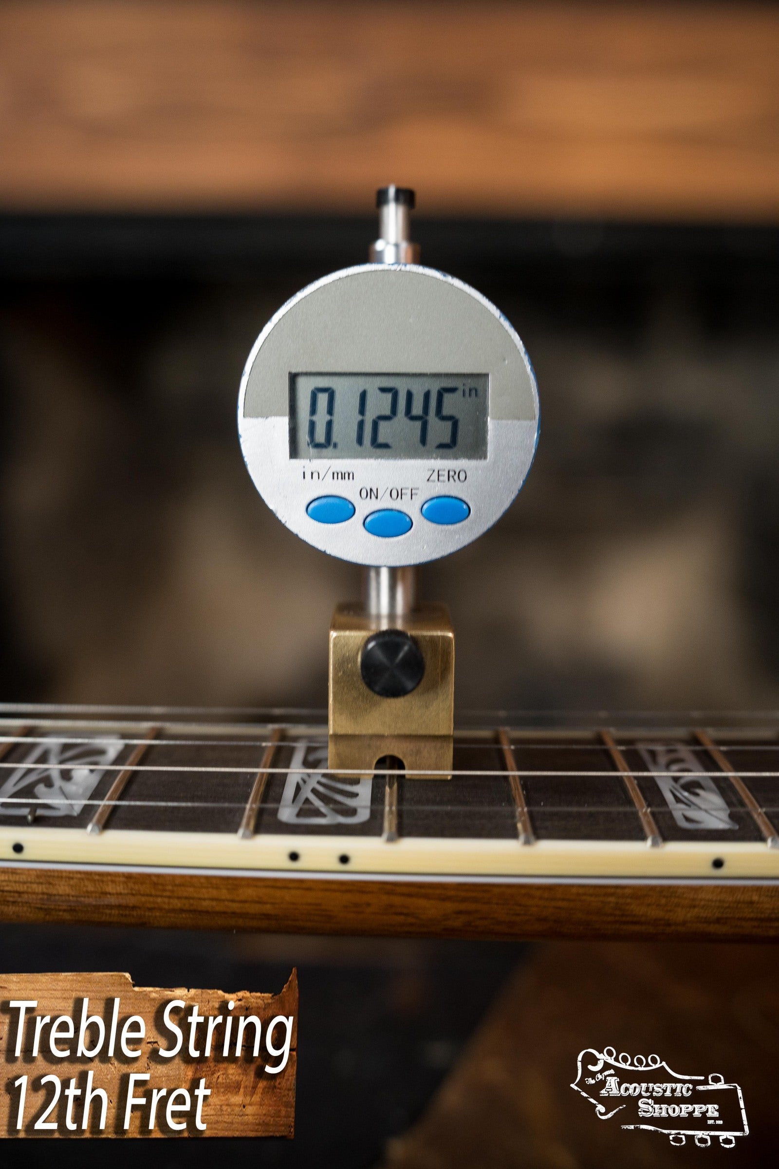 A digital gauge shows a 0.1245-inch string height at the 12th fret, with Treble String 12th Fret and The Acoustic Shoppe logo—ideal for bluegrass setups on the Deering Tony Trischka Silver Clipper Resonator Banjo by Deering Banjos.