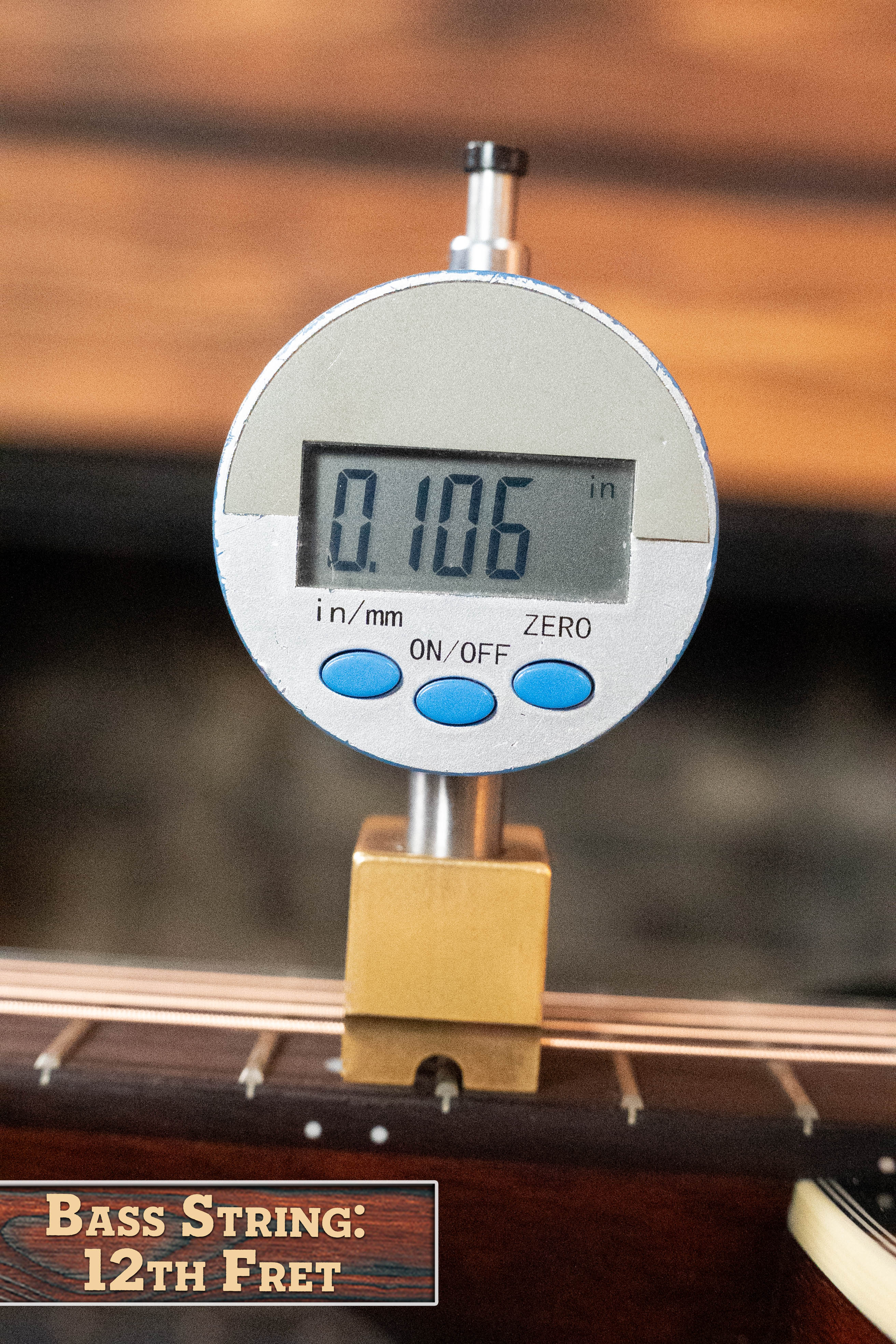 A digital caliper reads 0.106 inches as it measures the string height at the 12th fret of an *Eastman Guitars Dread-Not Certified Used* E6-LGSS-TC-SB Acoustic Guitar (#9323) with mahogany back and sides, labeled: Bass String: 12th Fret.