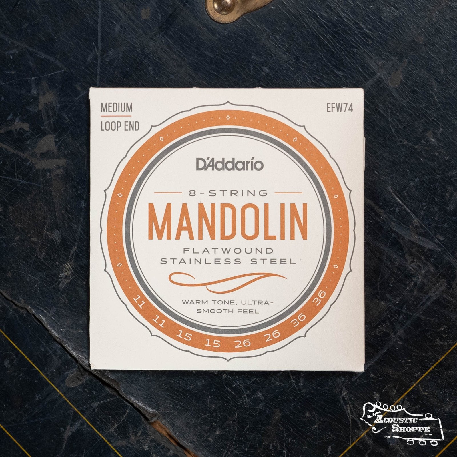 The D’Addario EFW74 Phosphor Bronze Flatwound Mandolin Strings (Medium, 11-36) offer an ultra-smooth feel ideal for jazz and are displayed on a dark surface.