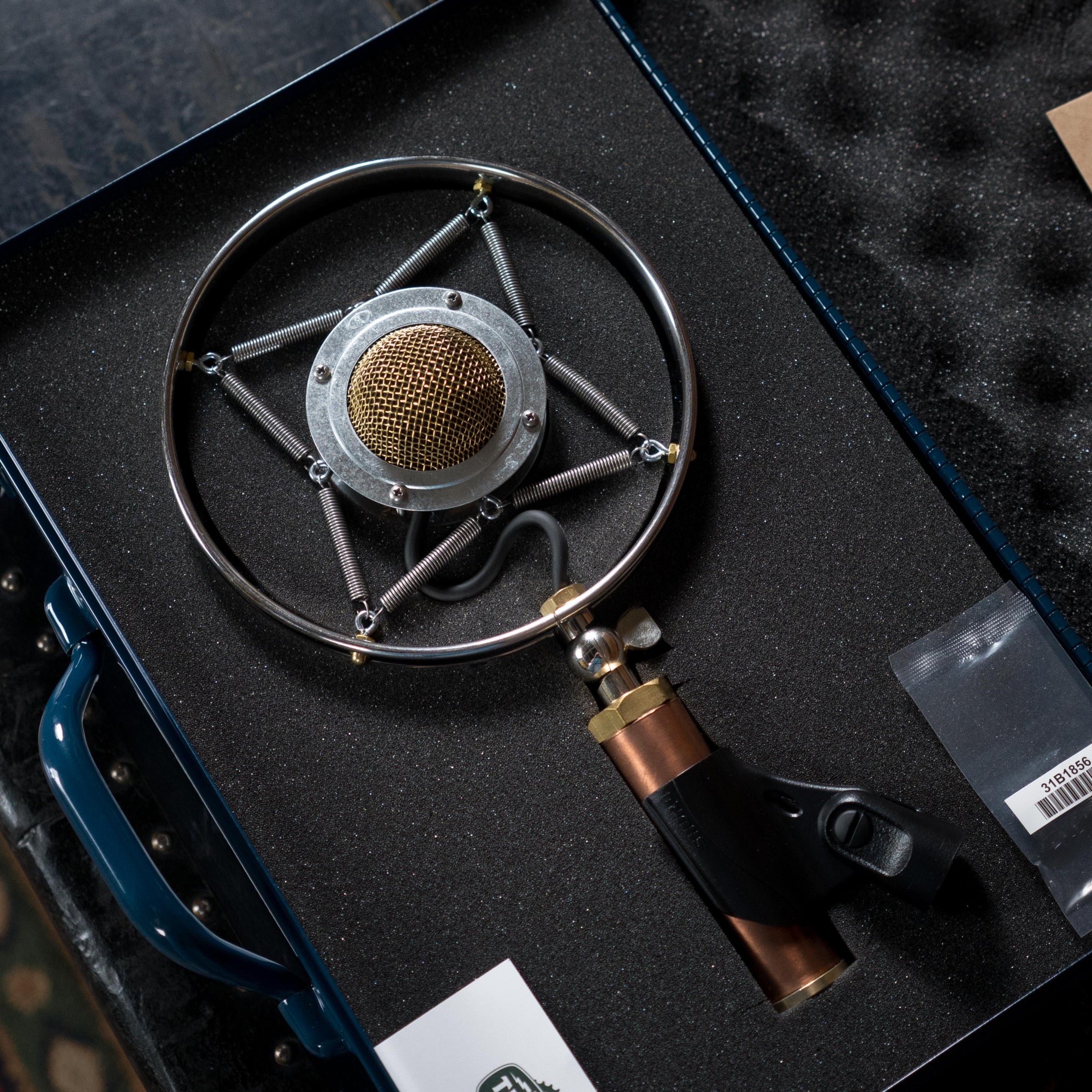 A close-up of the Ear Trumpet Labs Myrtle Microphone in its foam-padded case, featuring a gold mesh head, black and copper vintage-style body, metallic shock mount, clip, and accessoriesâall by Ear Trumpet Labs.