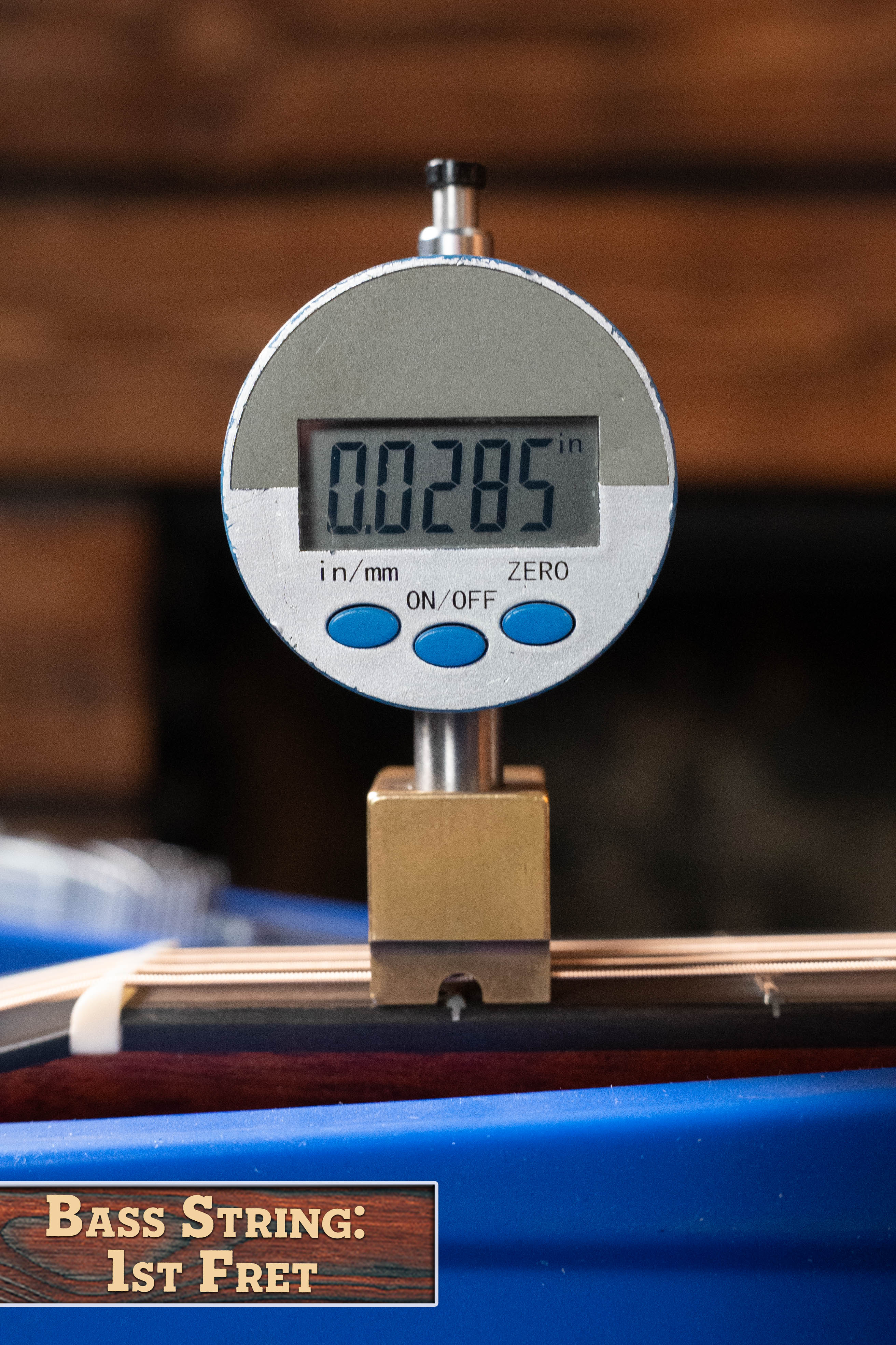 A digital gauge shows 0.0285 inches, measuring the bass string height at the 1st fret on an Eastman Guitars E1OM All Solid Sitka/Sapele Orchestra Model Acoustic Guitar (#7102), as noted in the lower left corner.