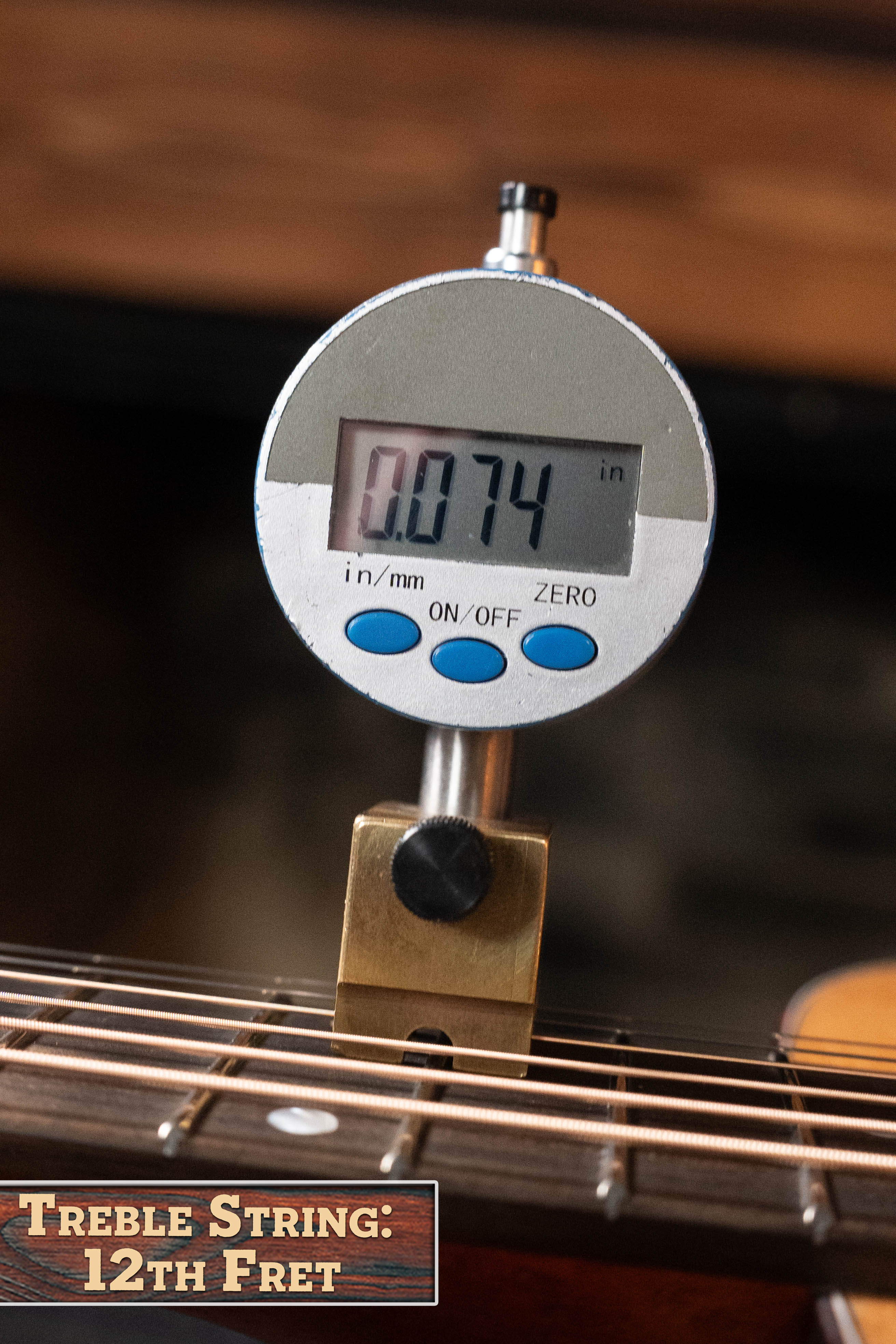 A digital gauge reads 0.074 inches above the treble string at the 12th fret of this Eastman Guitars E1OM All Solid Sitka/Sapele Orchestra Model Acoustic Guitar #7102 (label: Treble String, 12th Fret).