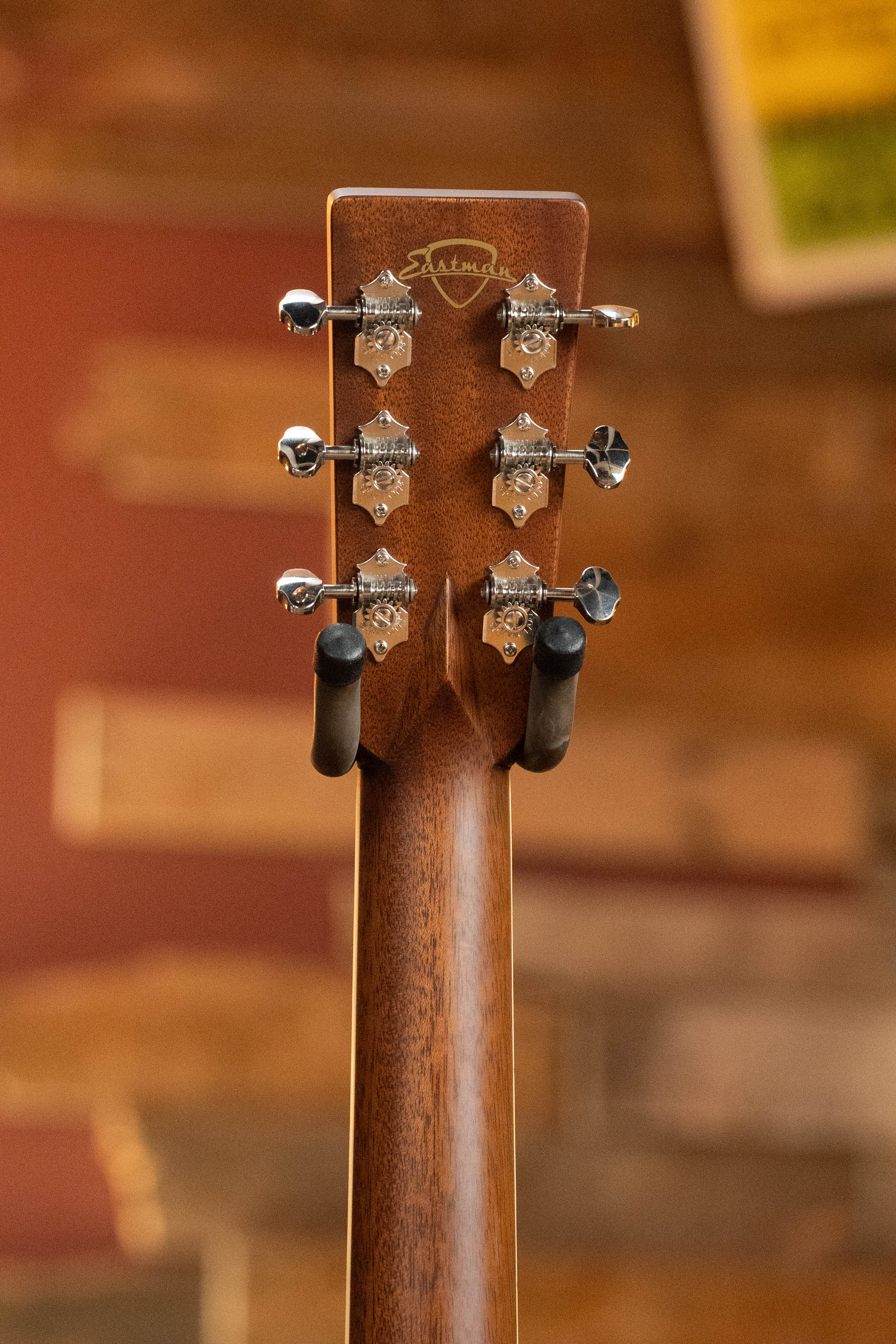 Close-up of an acoustic guitar headstock with six tuning pegs and the Martin logo, set against a warm, blurred background—ideal for comparing details with the Eastman Guitars E20D-LSH-TC Thermo-Cured Adirondack/Rosewood Dreadnought #8072.