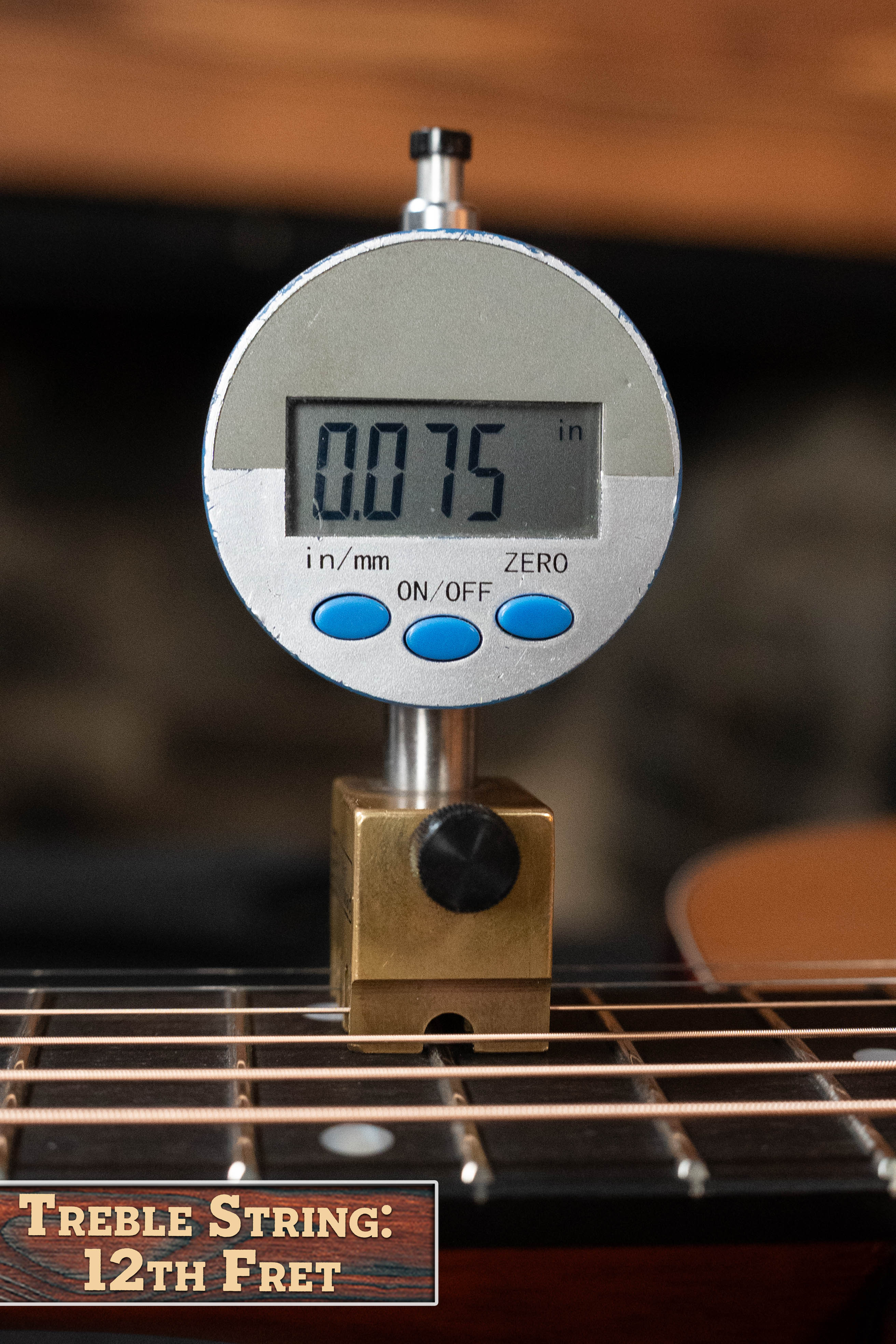 A digital gauge shows 0.075 inches above the treble string at the 12th fret of an Eastman Guitars E2OM Cedar/Sapele Orchestra Model Acoustic Guitar #9010. A sign in the lower left reads, Treble String: 12th Fret.
