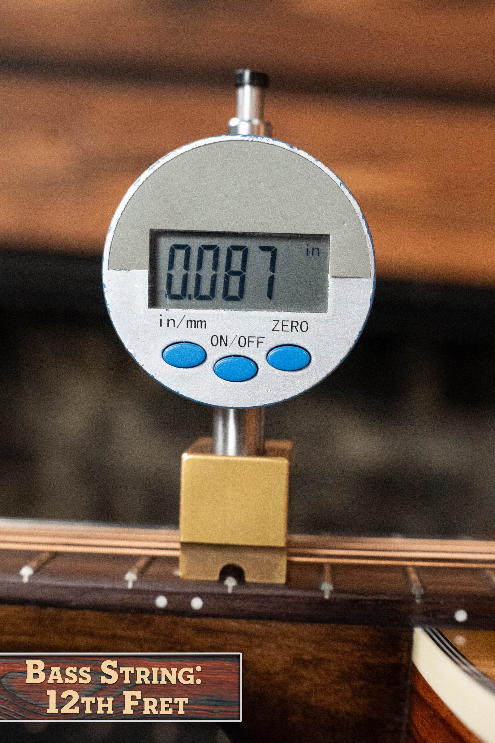 A digital gauge shows a 0.087-inch string height at the 12th fret of the Eastman PCH2-TG Travel Acoustic Guitar (#9714) by Eastman Guitars—ideal for setups on laminated rosewood fingerboards.